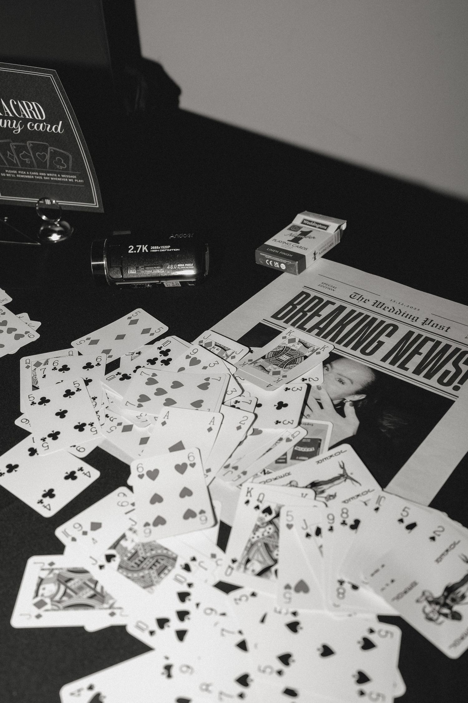 Playing cards scattered across a dark table in black and white photography.