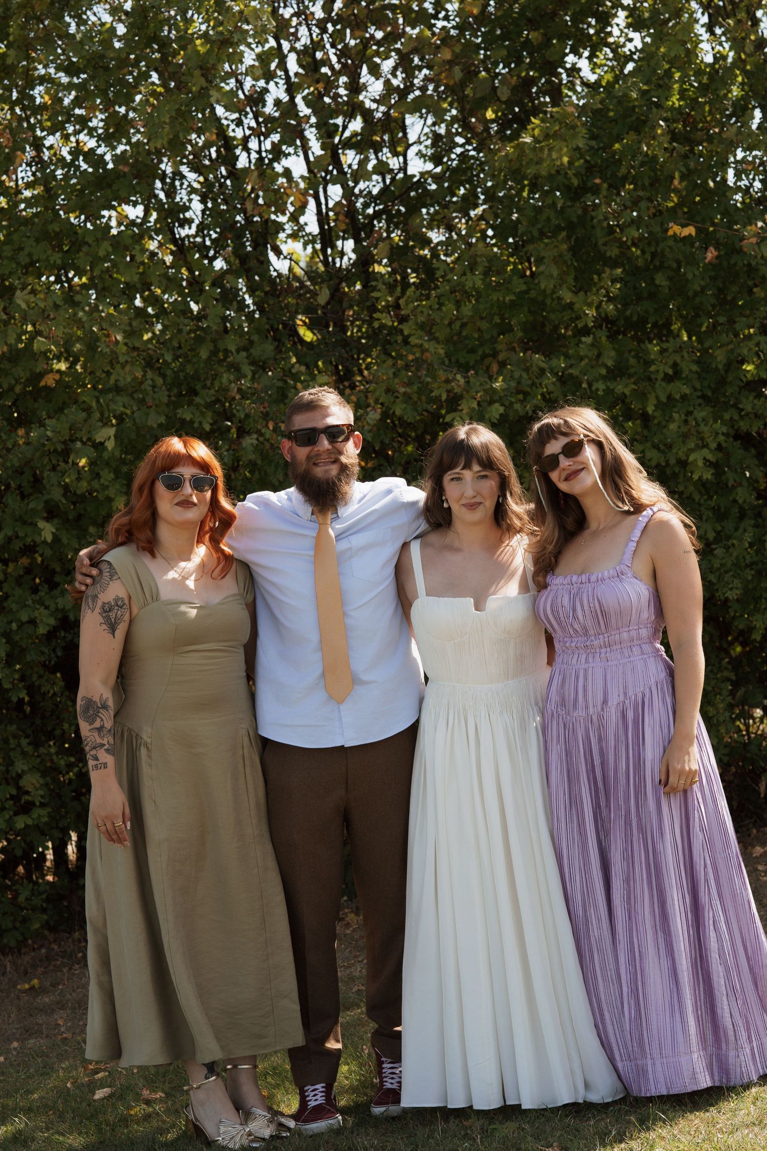 Wedding party group photo with people wearing coordinated dresses in earth tones and pastels.