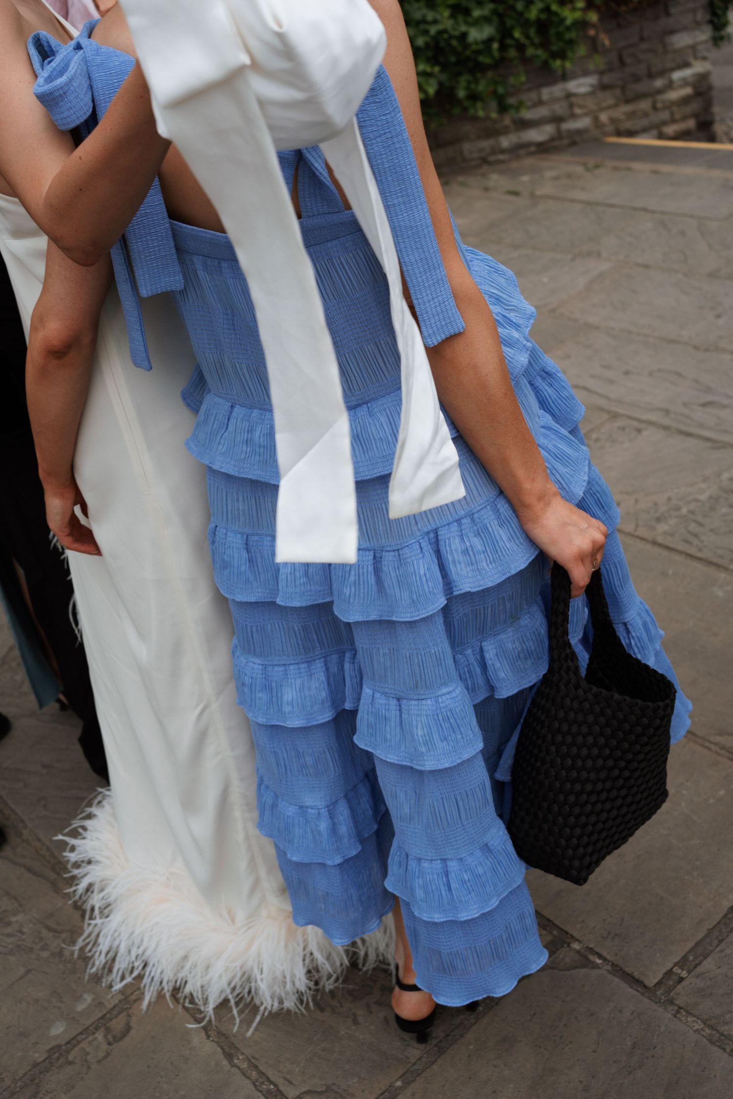 Close-up detail of blue tiered bridesmaid dresses next to a white feathered wedding gown.