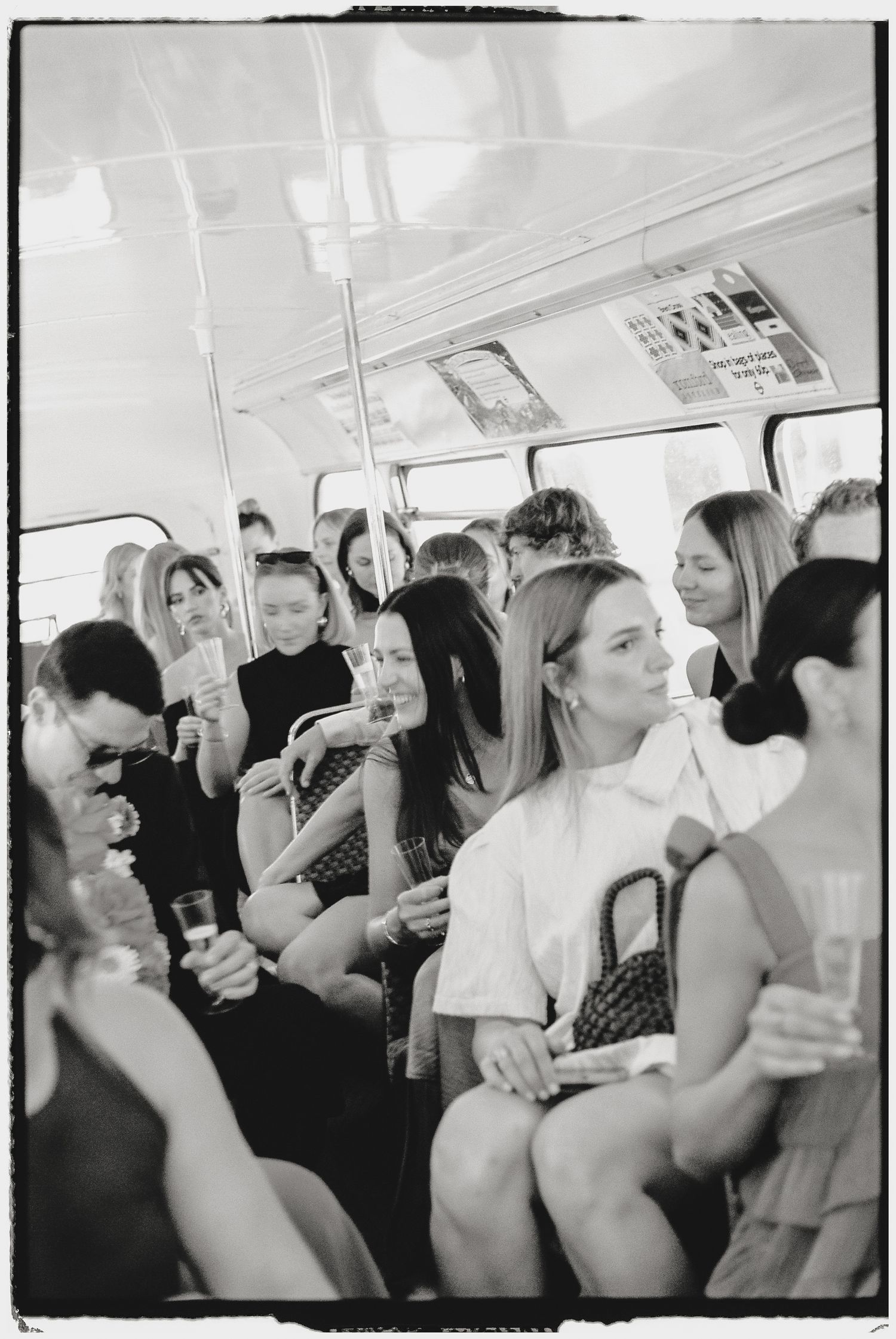 Black and white photo of wedding guests celebrating on a crowded party bus.