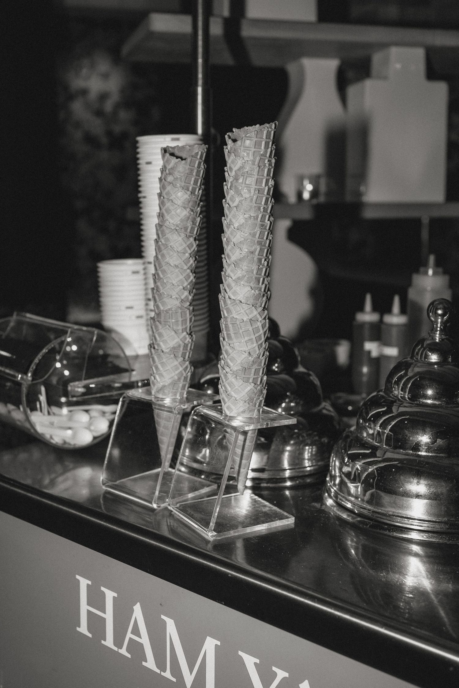 Black and white photo of catering setup with stacked glasses and serving equipment.