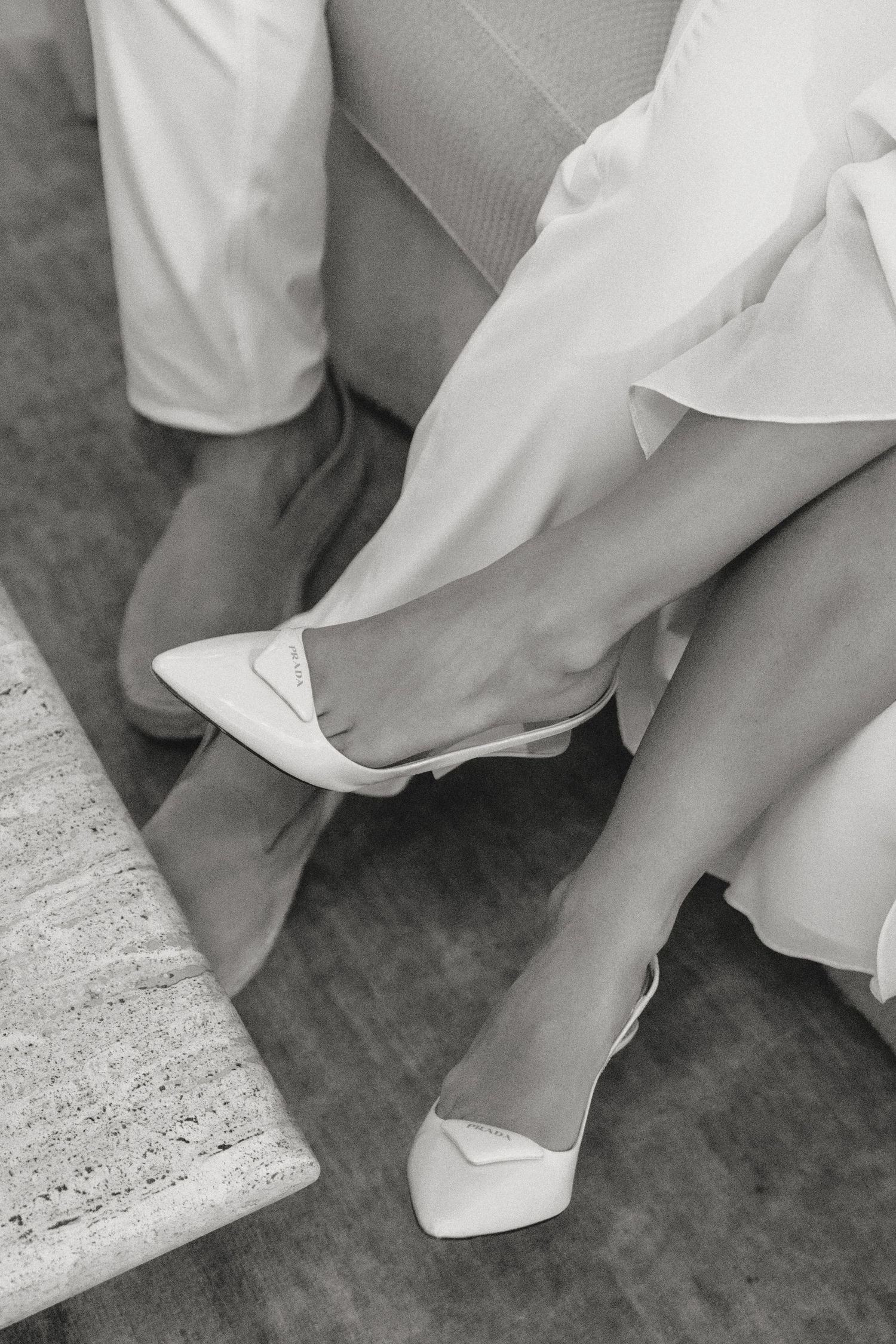 Close-up black and white photo of white shoes and dress fabric details.
