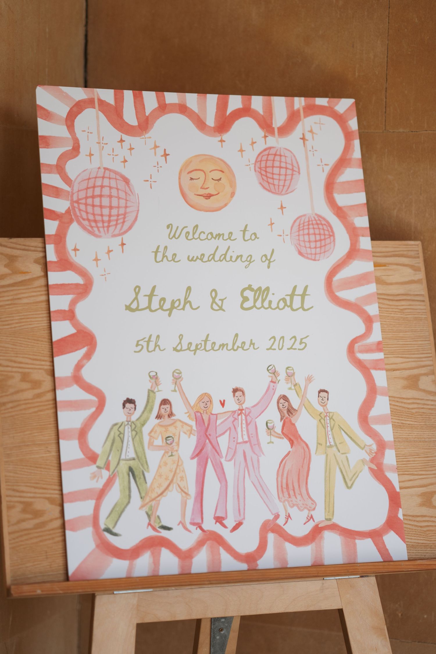 Whimsical wedding welcome sign with pink and gold illustrations of dancing figures.