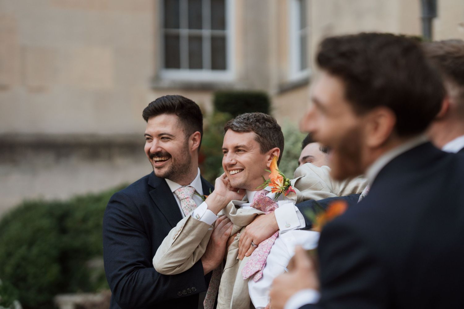 Candid wedding party photo showing joyful laughter outdoors.
