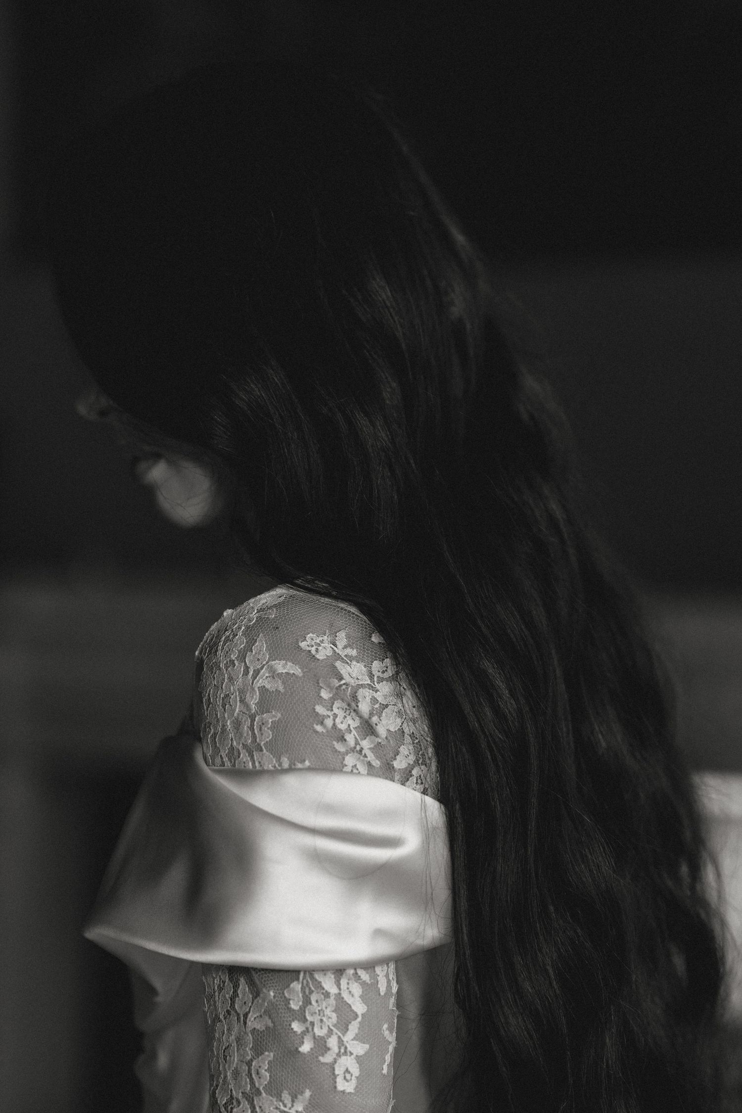 Black and white portrait showing detailed lace sleeve of wedding gown.