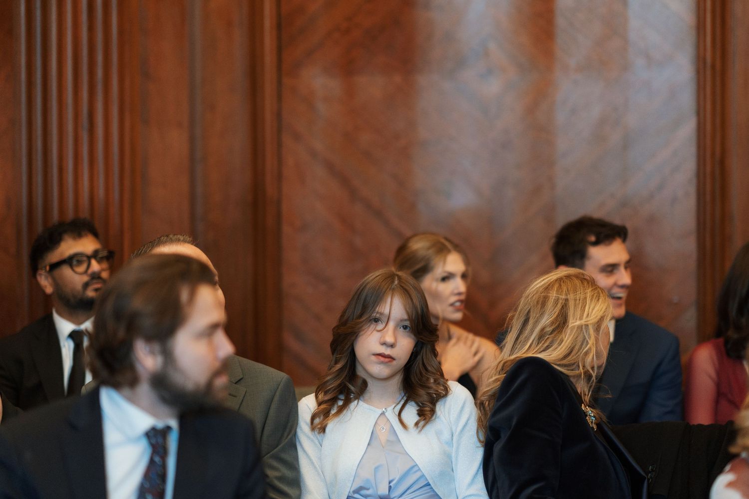 People seated in a wood-paneled auditorium during an event.