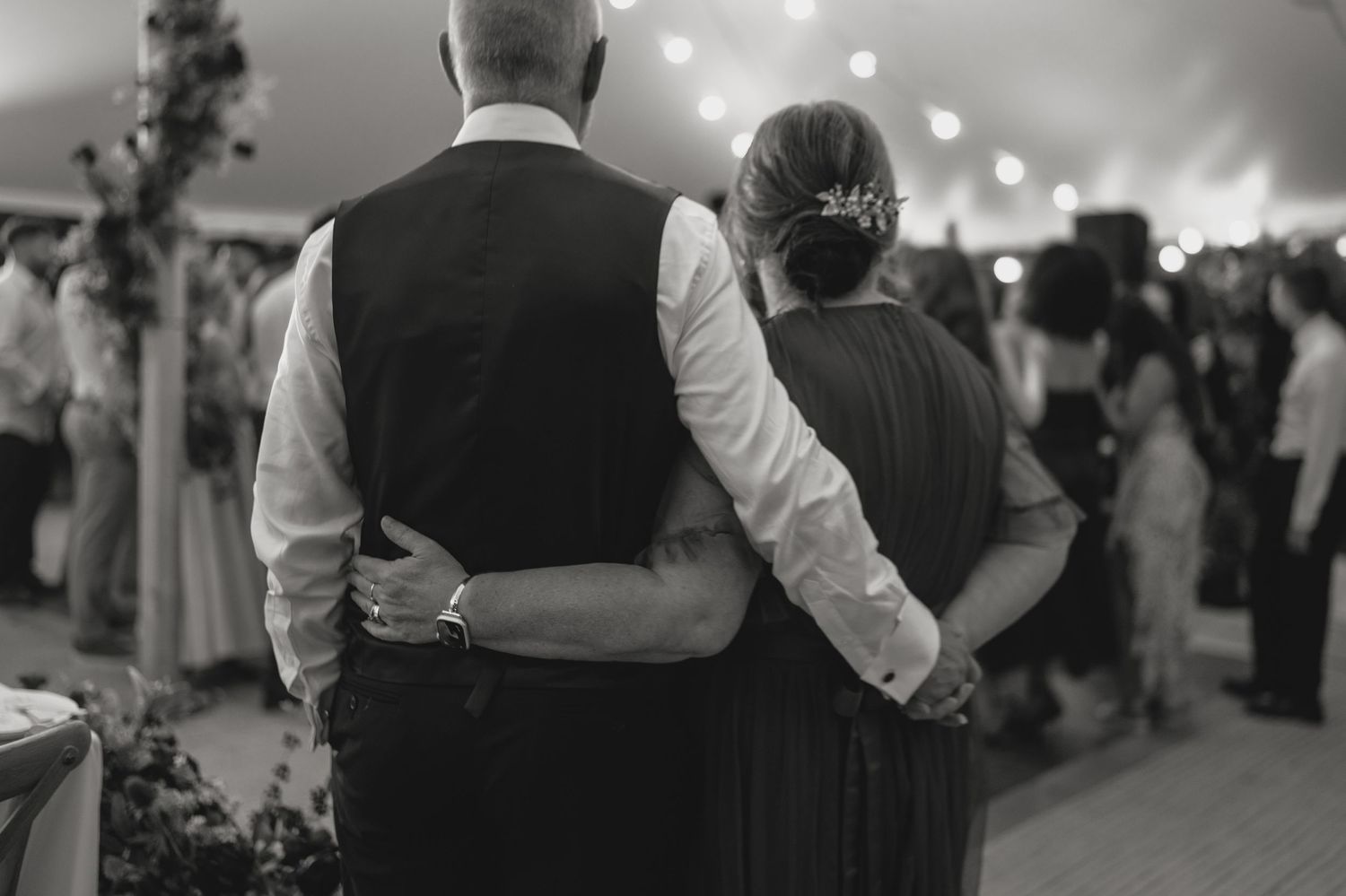 Black and white photo of a couple embracing at a wedding reception.