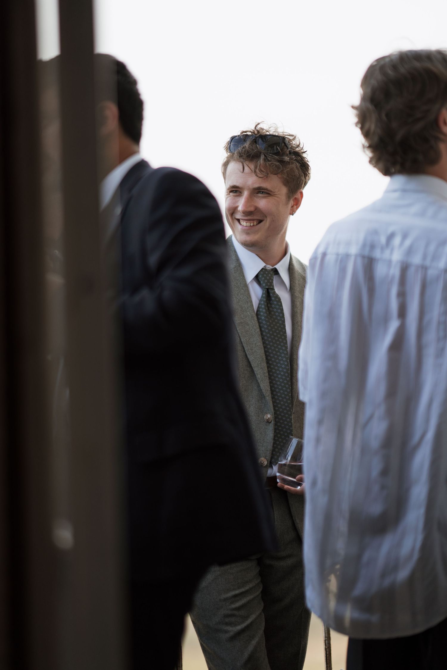 Guest in formal attire smiles during conversation at social gathering.