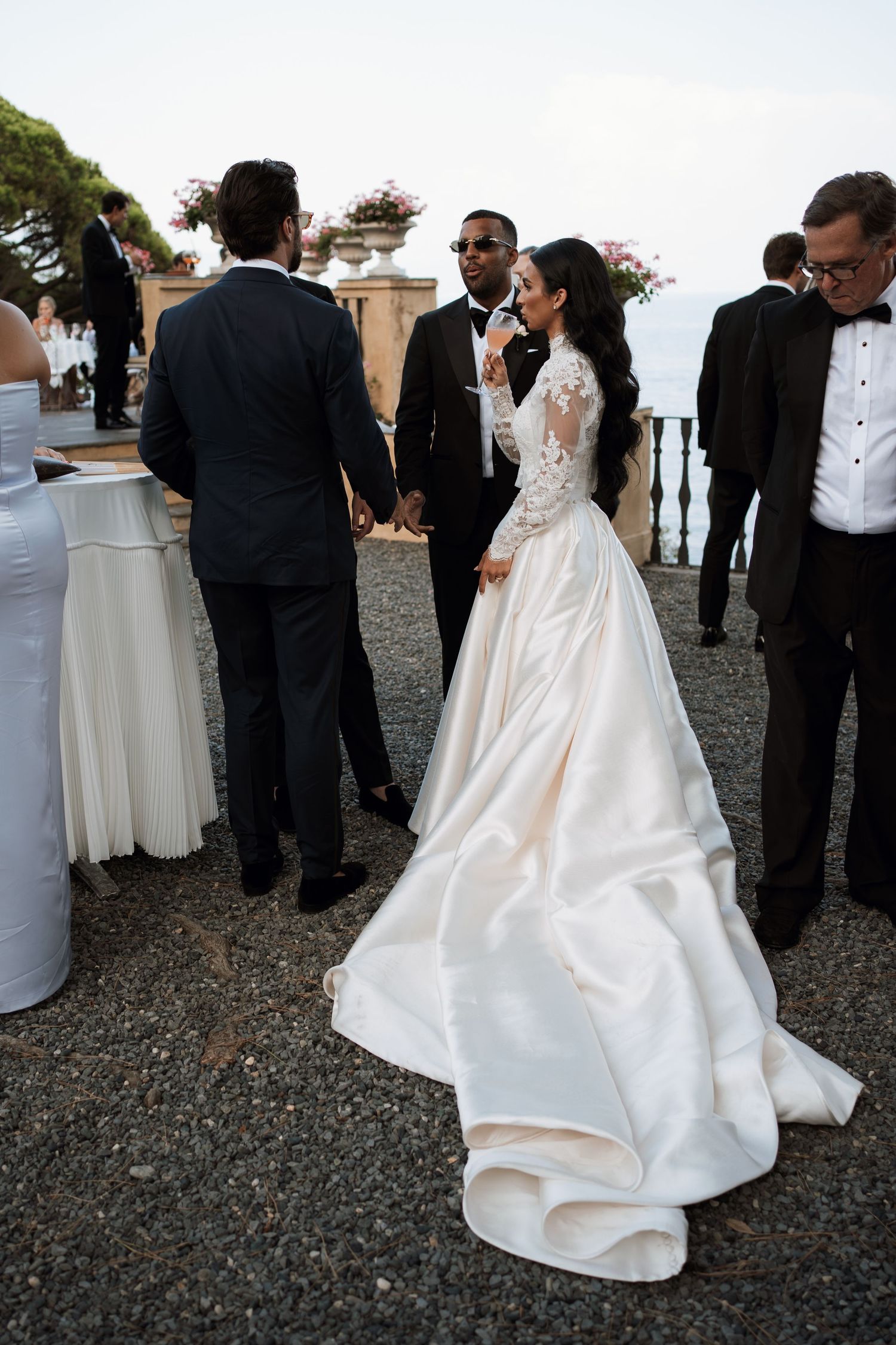 Wedding celebration with guests in formal attire gathered on a coastal terrace.