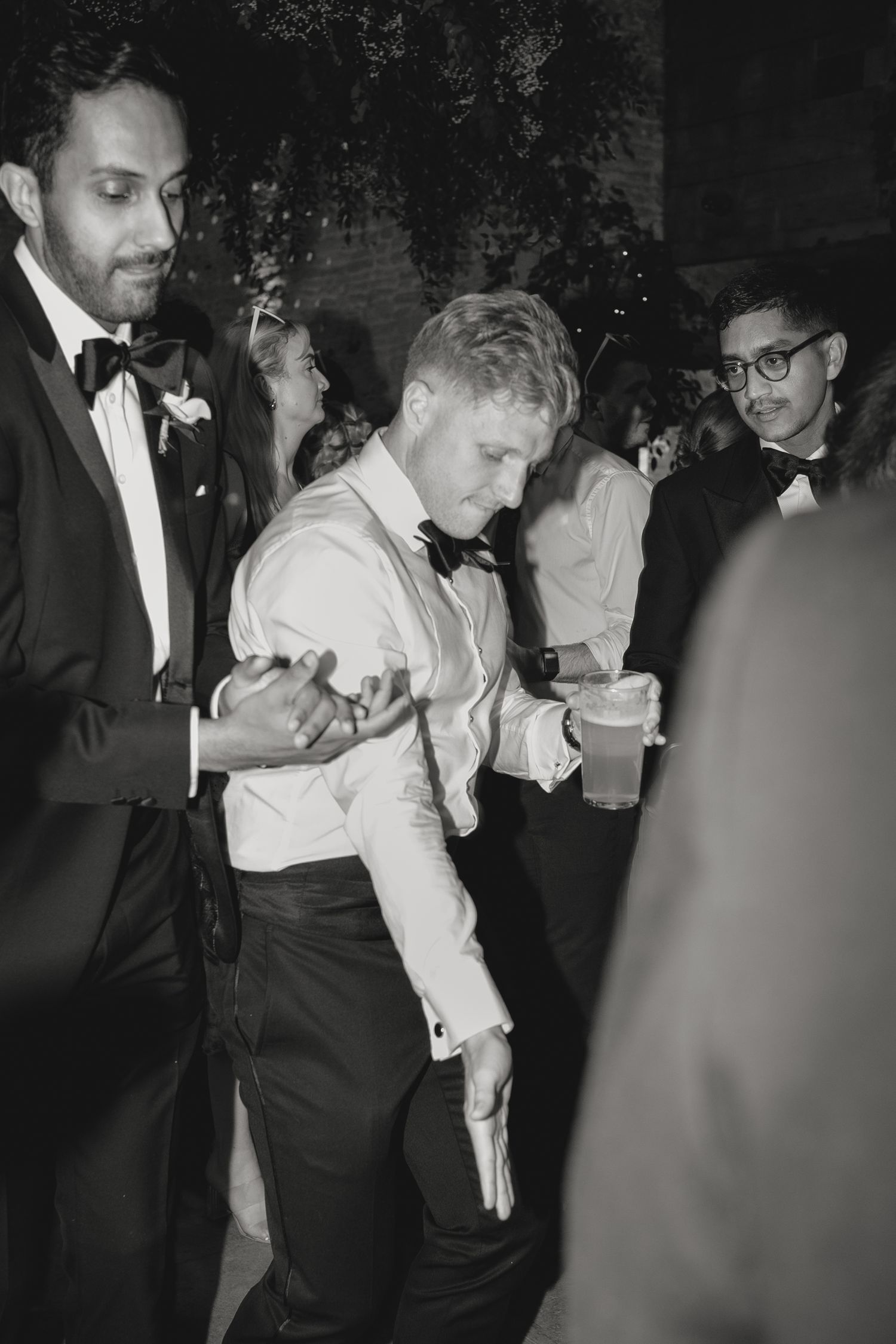 Black and white photo of guests dancing at formal celebration.