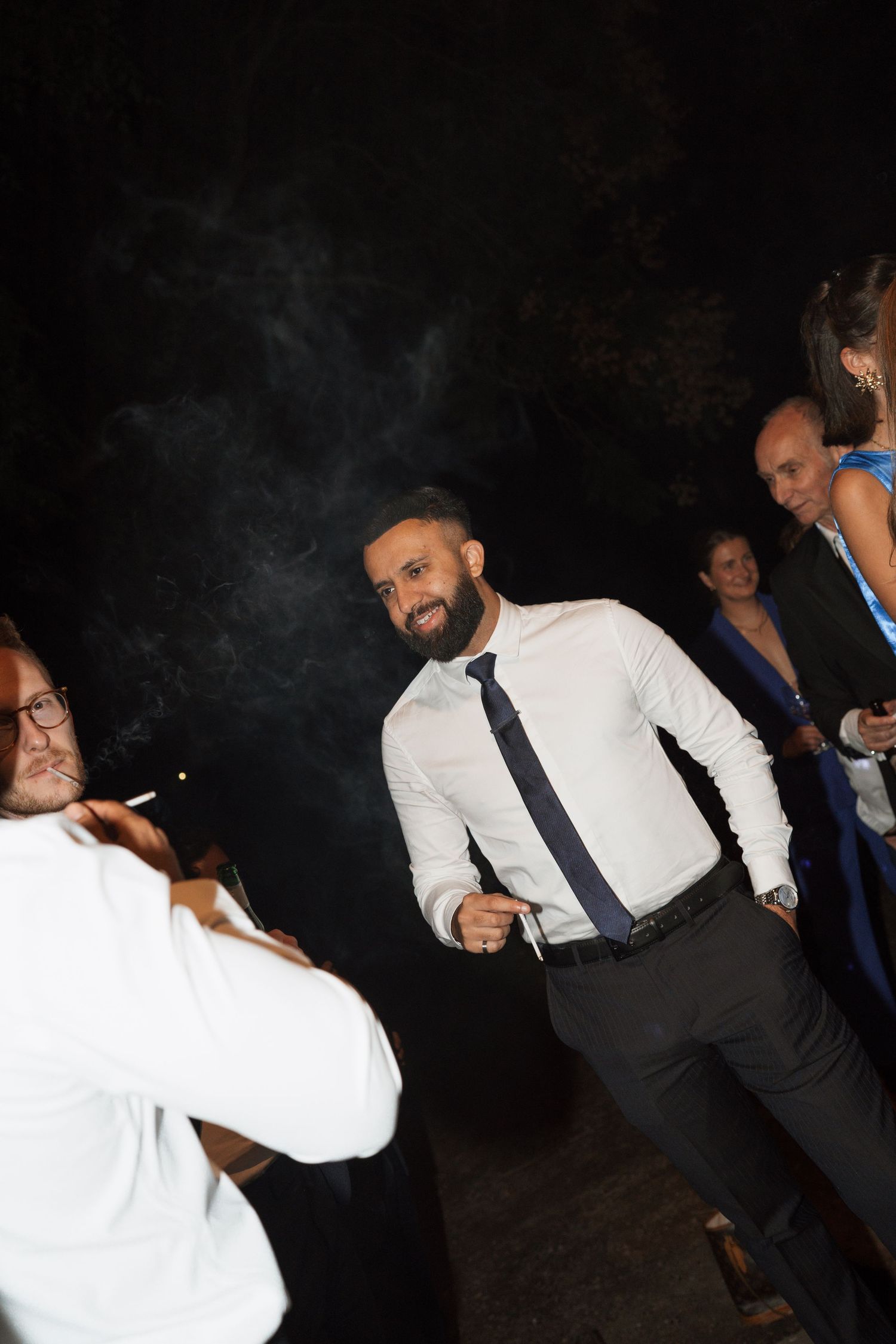 People in formal attire dancing and celebrating at a dark party venue.
