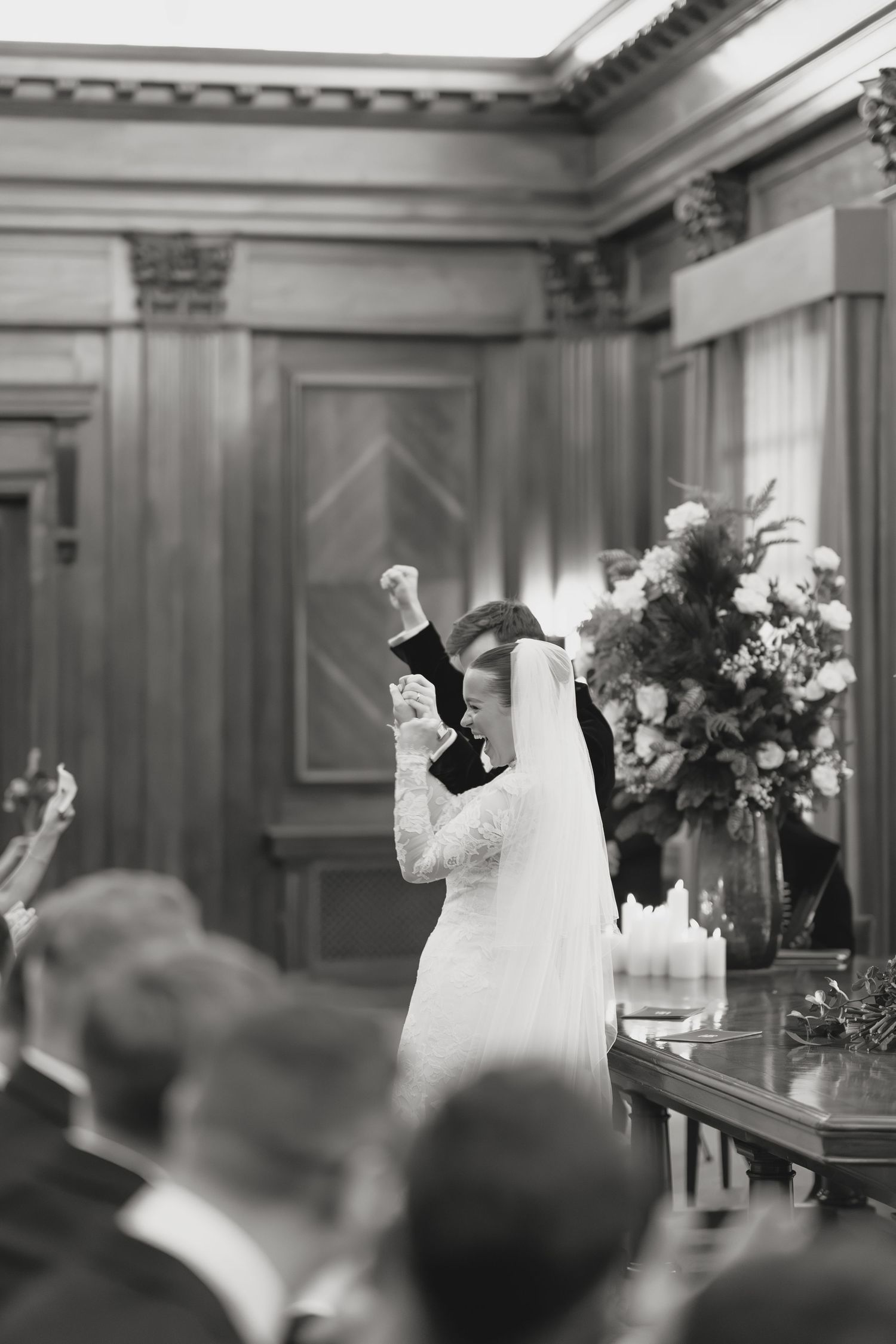 A bride in white dress raising her arms during a wedding celebration.