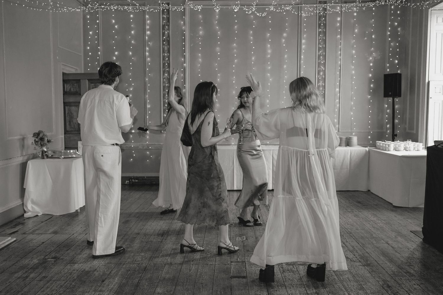 Wedding reception hall decorated with hanging string lights in black and white.