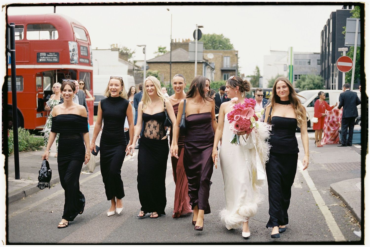 Wedding guests walking down a city street in formal attire.