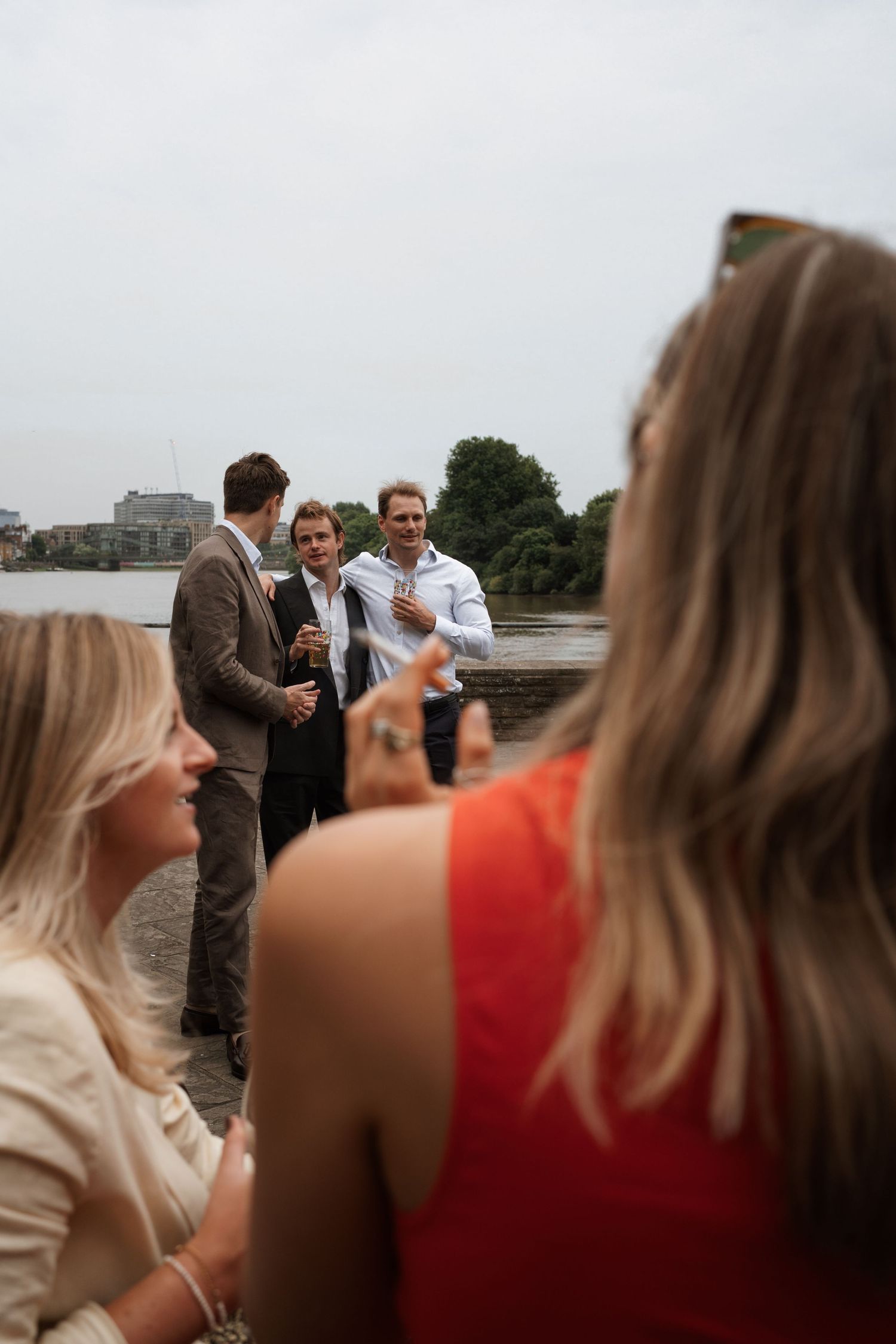 Wedding guests in colorful attire gather for conversations during an outdoor celebration.