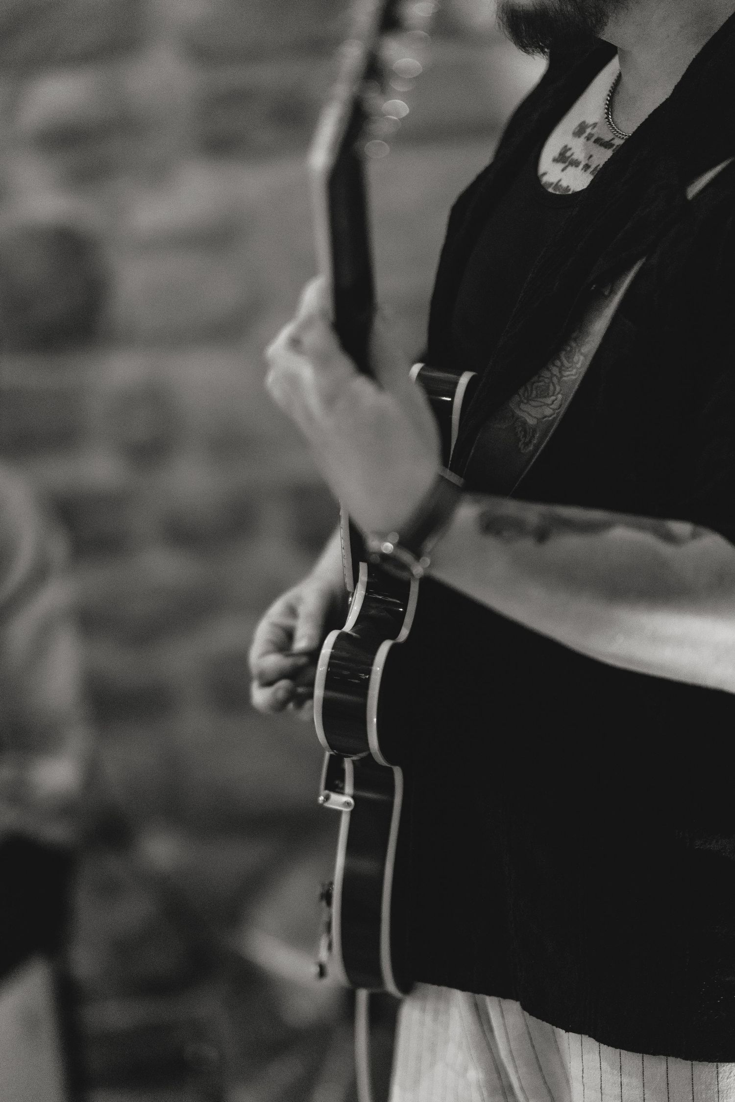 Black and white photo of musician playing guitar at wedding reception.