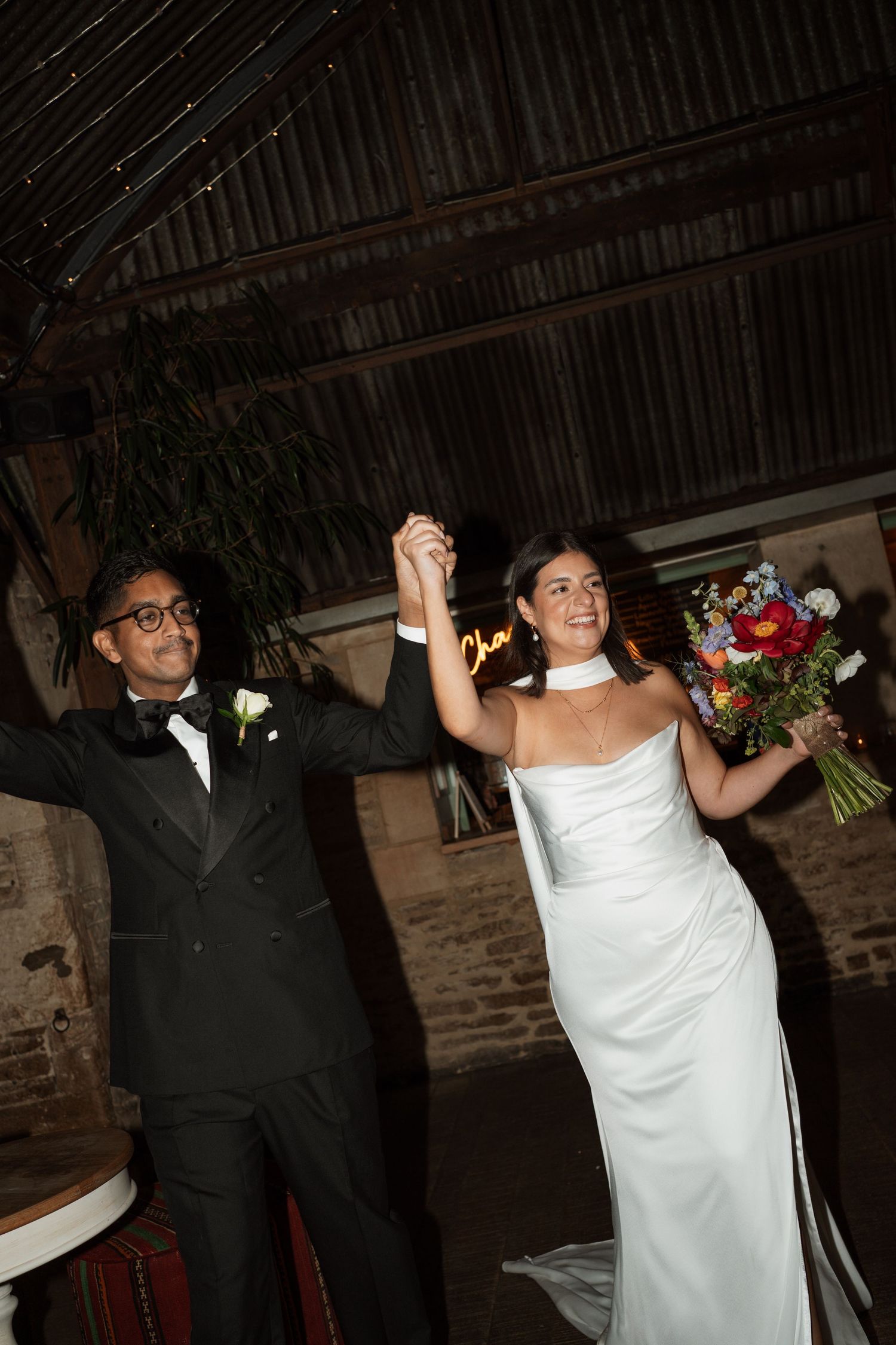 A couple celebrates during their wedding reception in a rustic brick-walled venue.