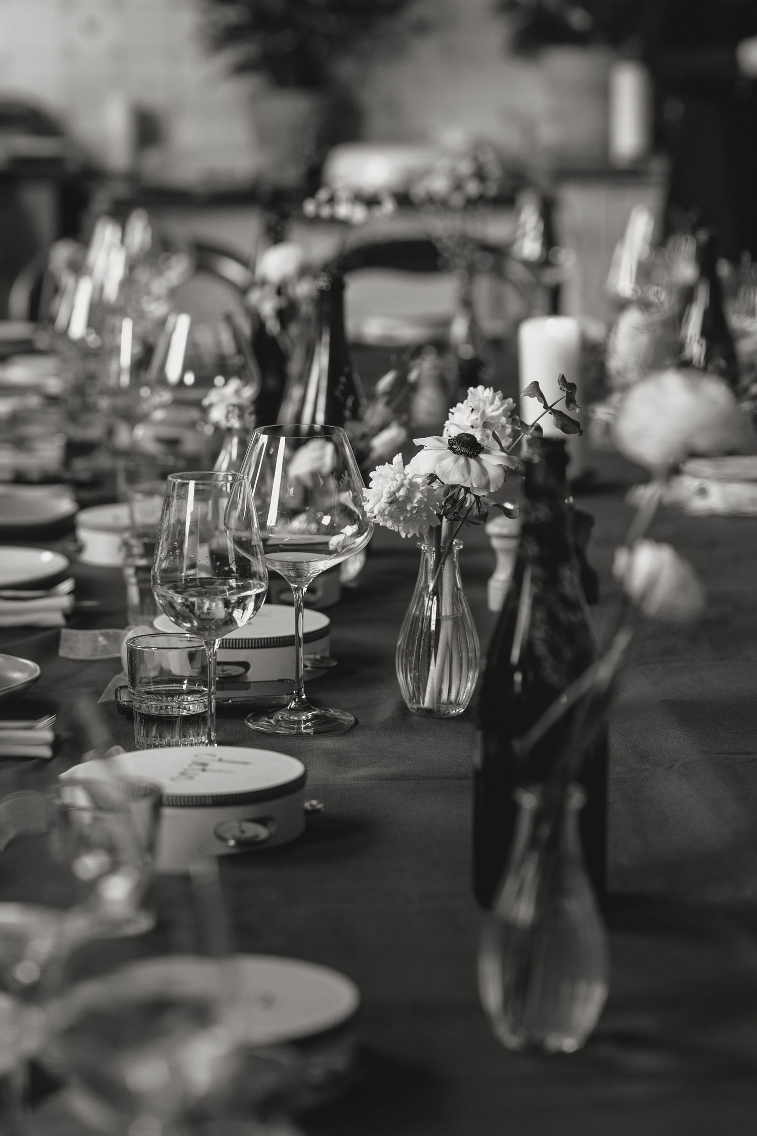 Elegant table setting with wine glasses and floral arrangements on a dark tablecloth.