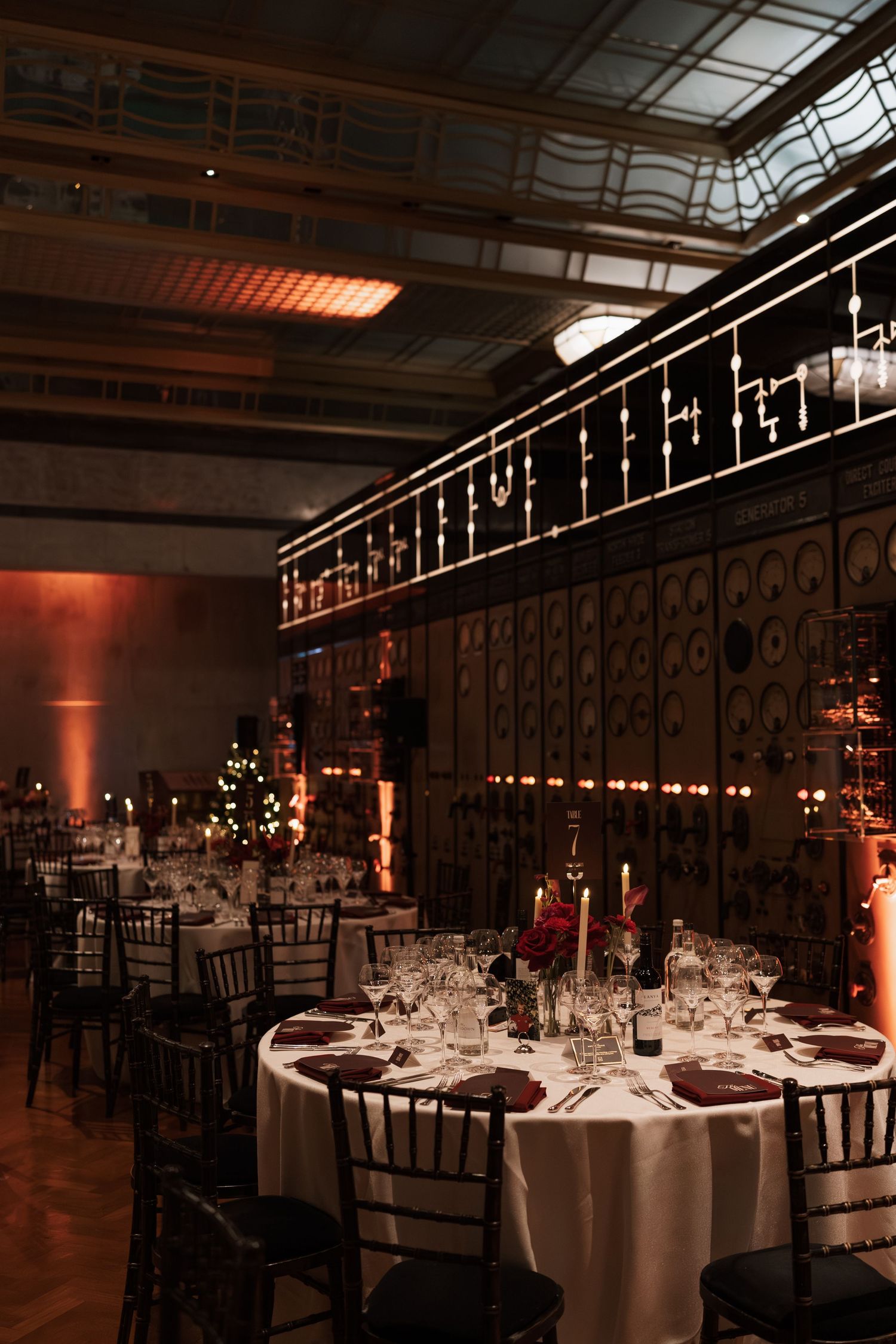 Formal reception venue with round tables and dramatic red uplighting creating an elegant atmosphere.
