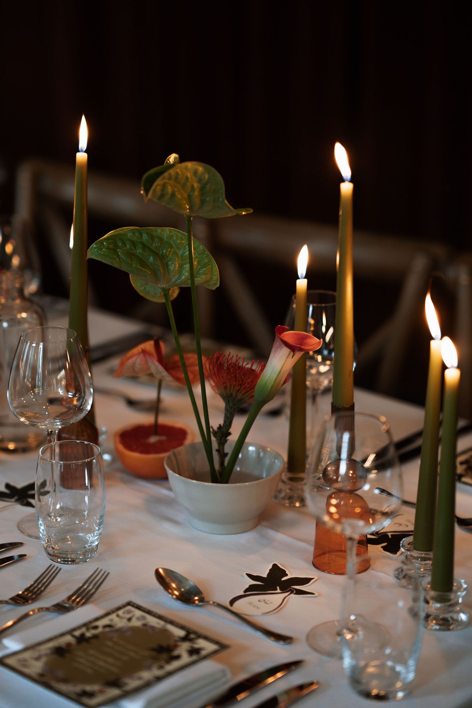 Elegant table setting with lit candles, wine glasses and floral centerpieces.