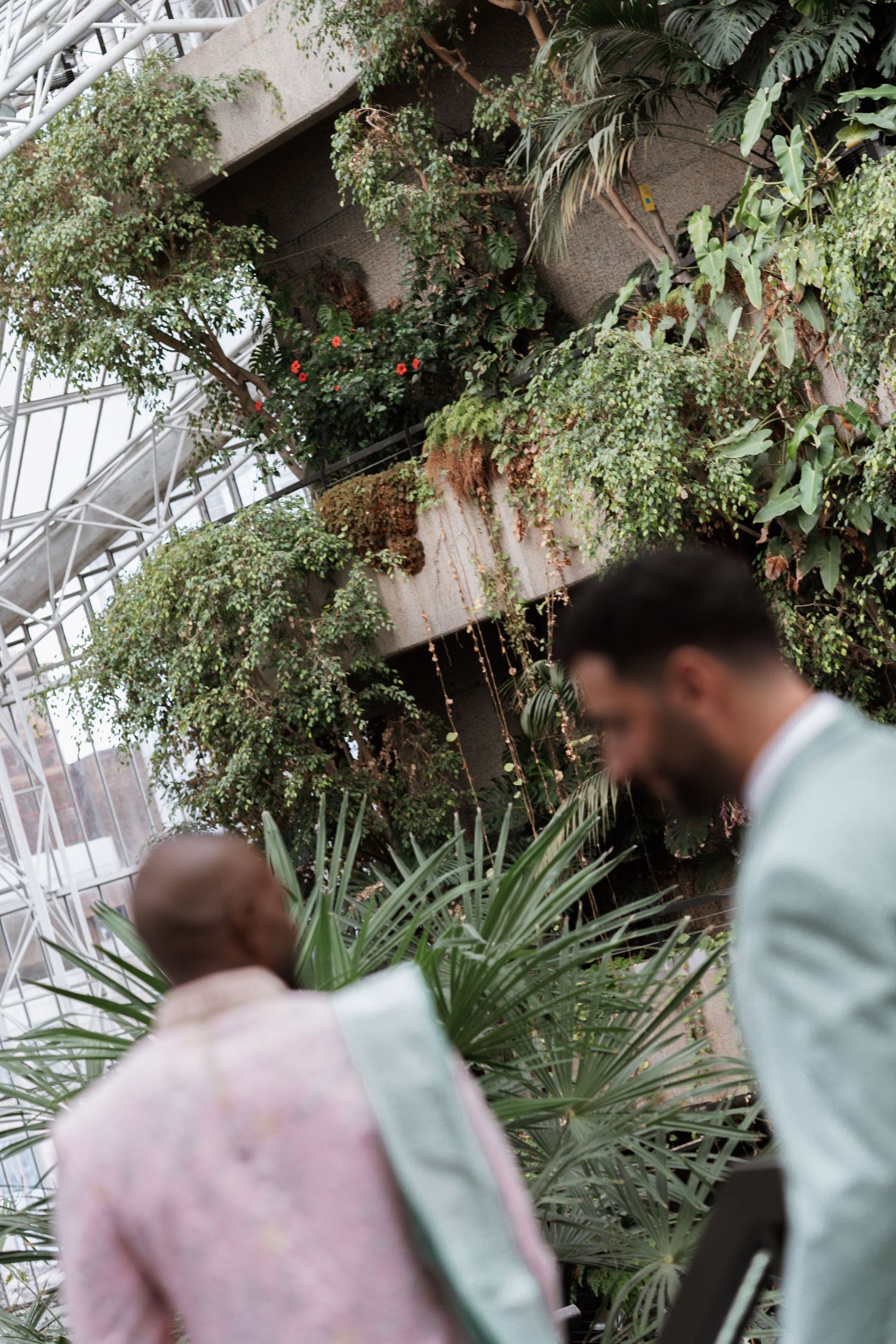 Couple in pastel formal wear photographed in a greenhouse with tropical plants.