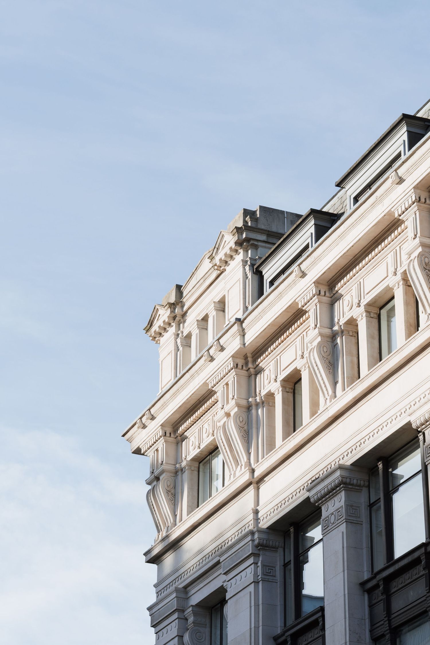 White ornate architectural details of a classic building facade against blue sky.