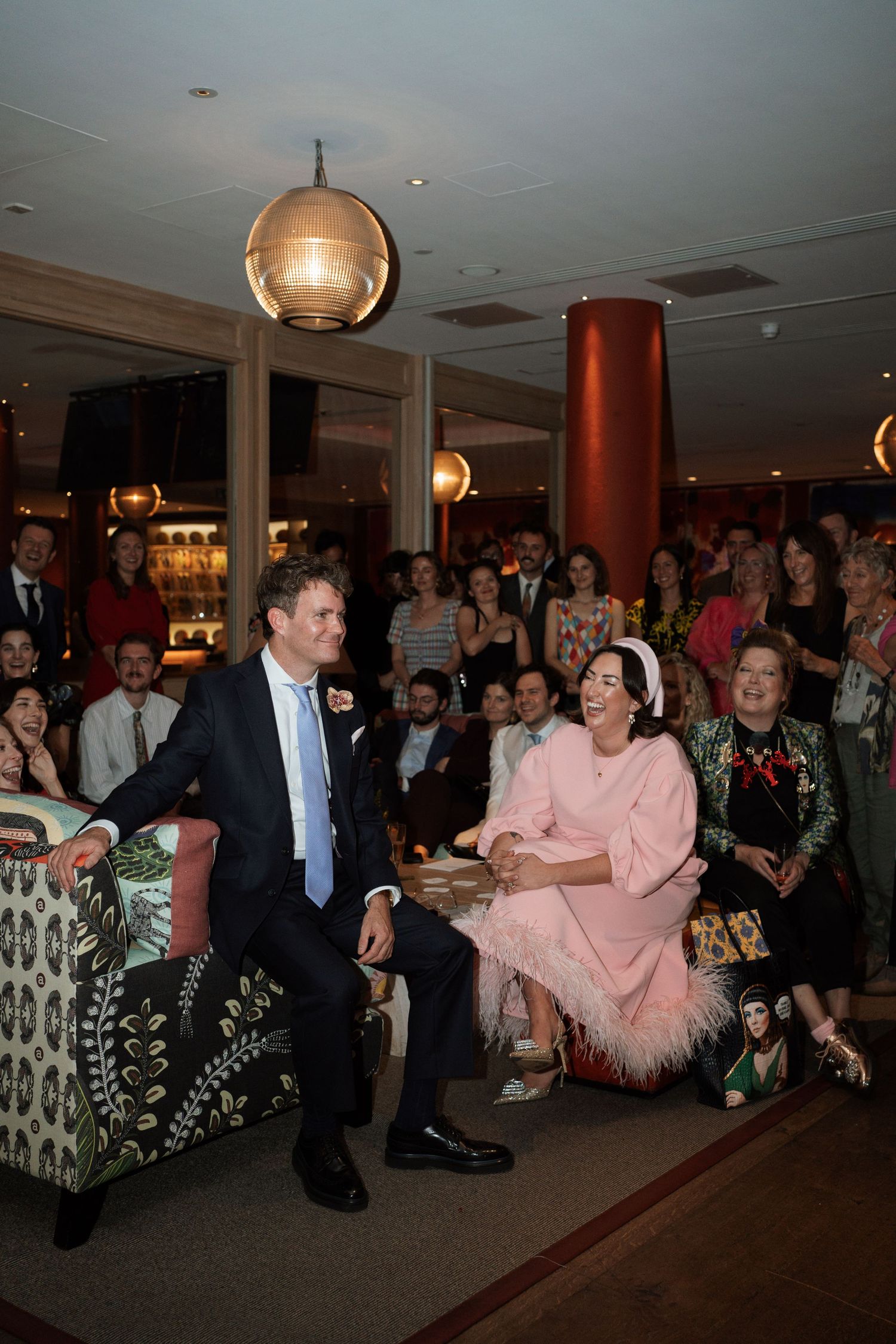 Wedding reception scene with guests watching a performance in an elegant venue.