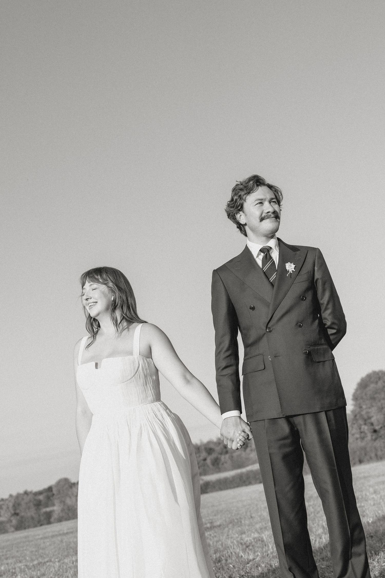 Black and white wedding portrait of a couple in a field.
