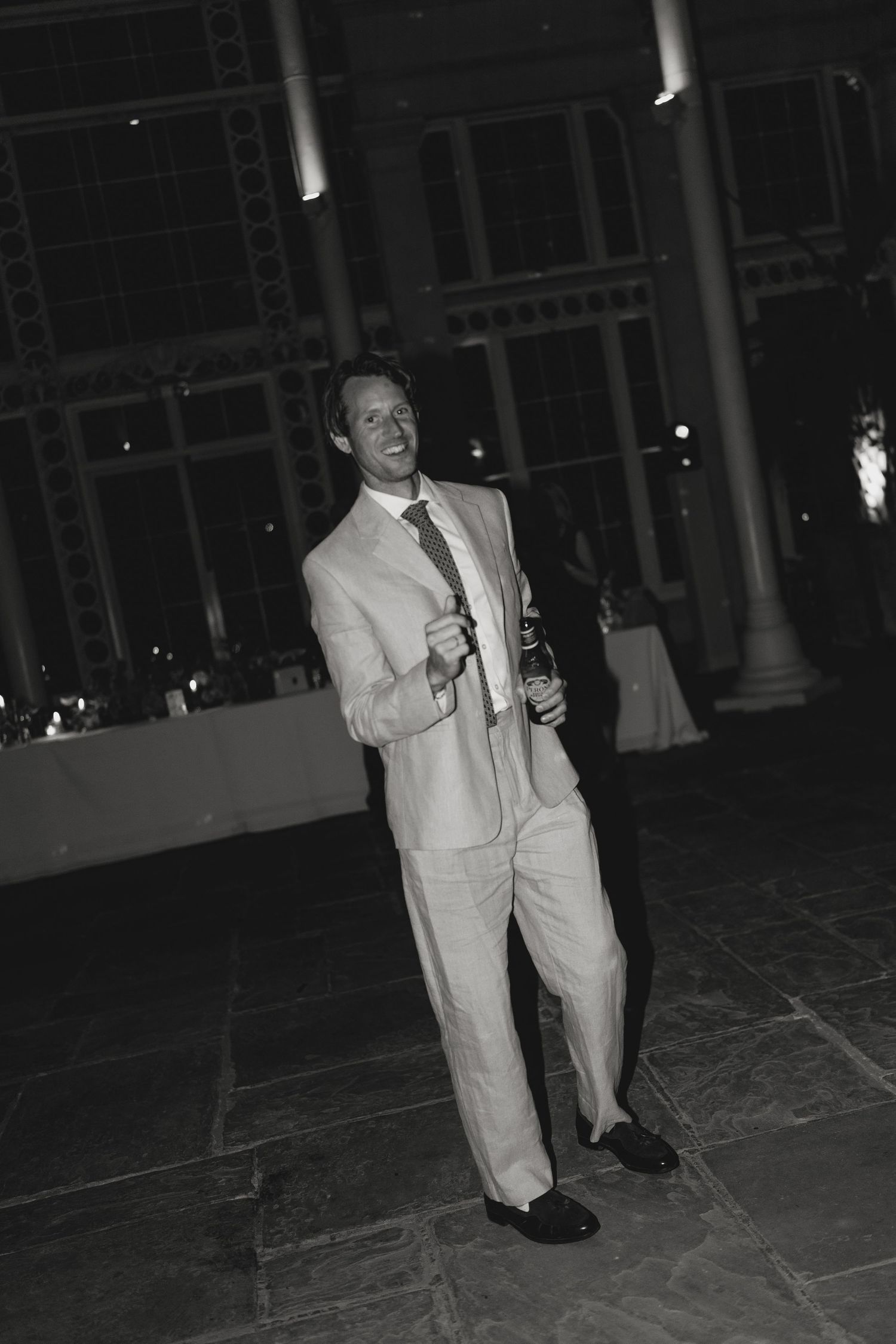 Person in light colored suit dancing on a tiled floor at an indoor venue.