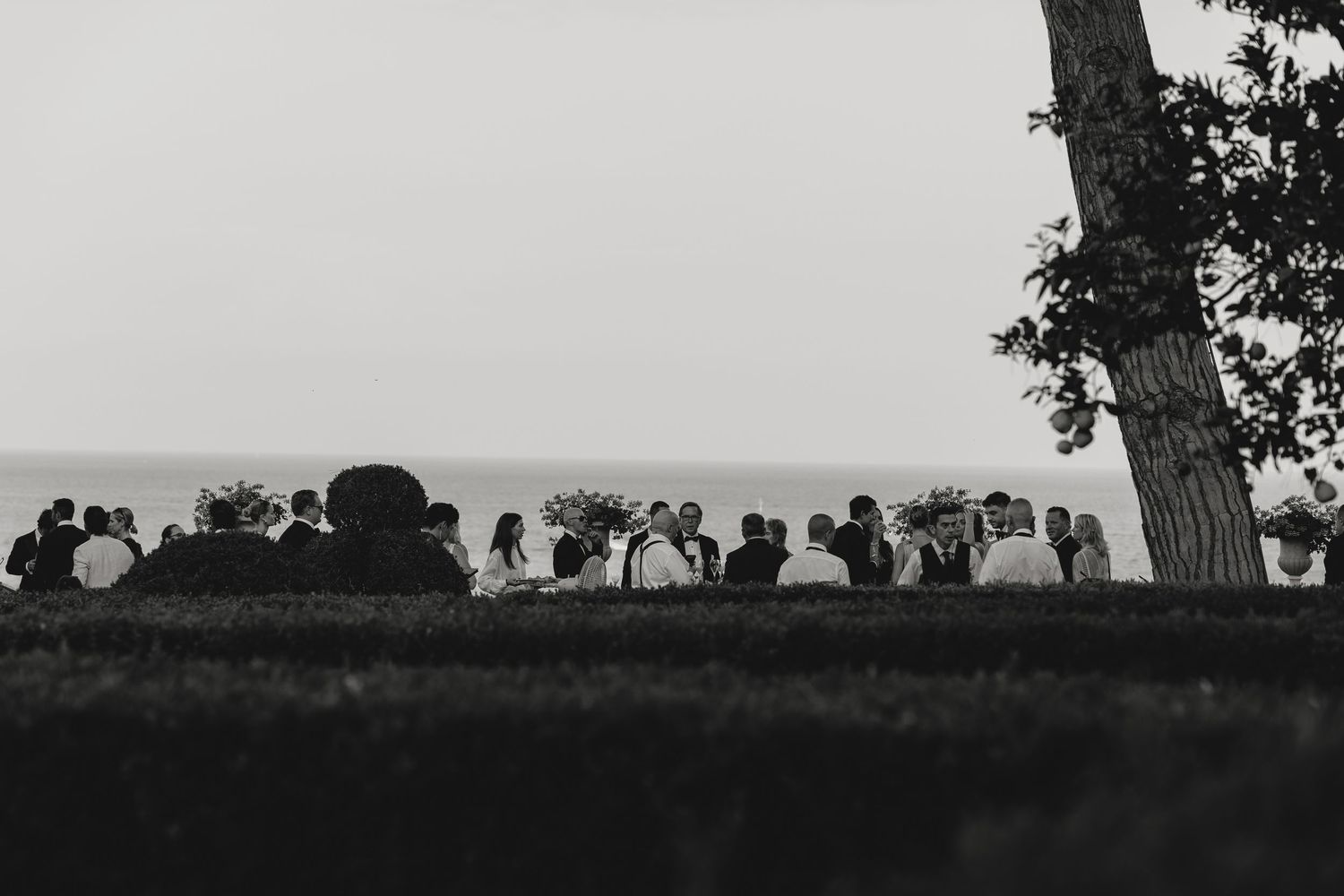 Silhouettes of guests standing outdoors during sunset at an elegant wedding reception.