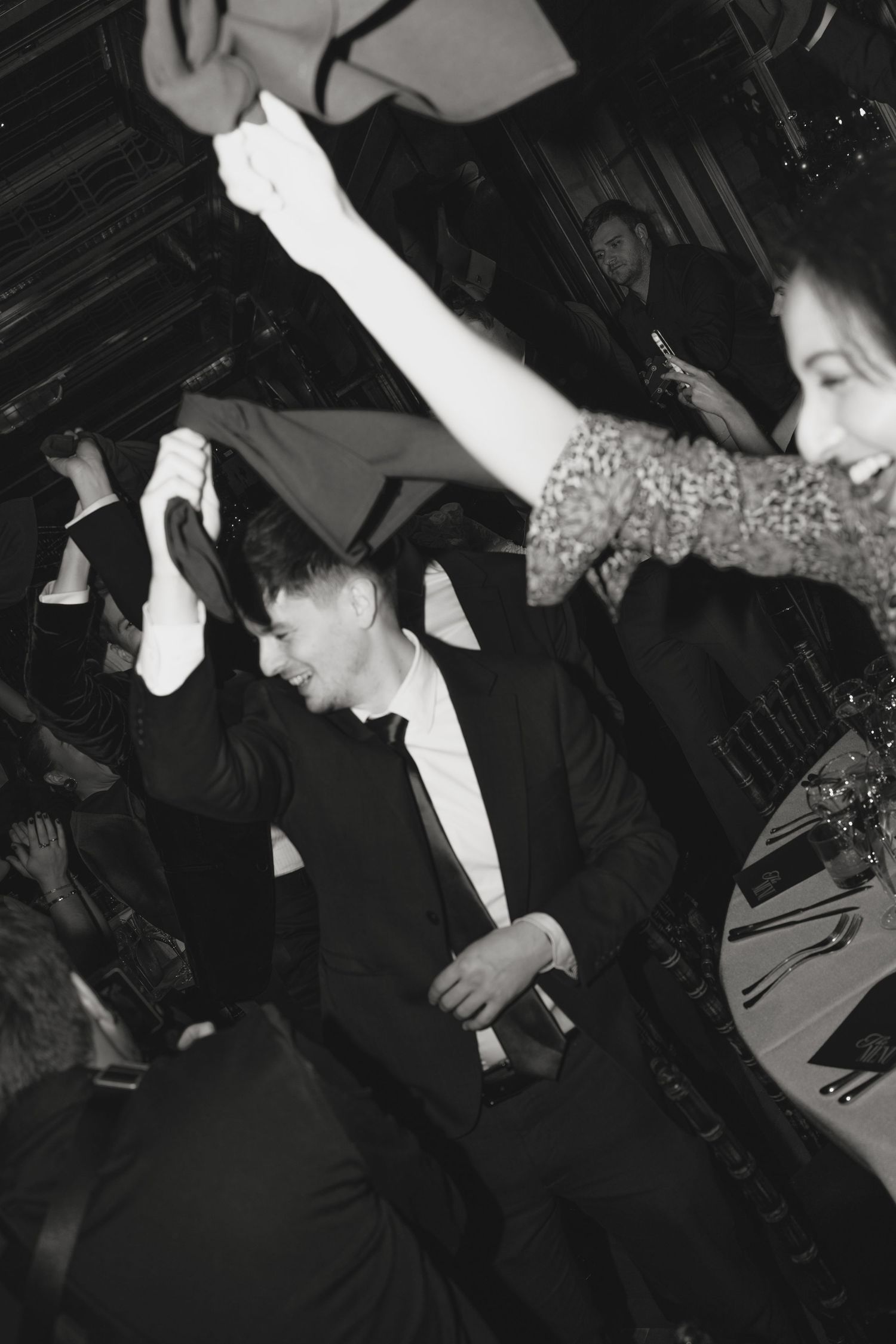 Black and white photo capturing energetic dancing and celebration at formal event.