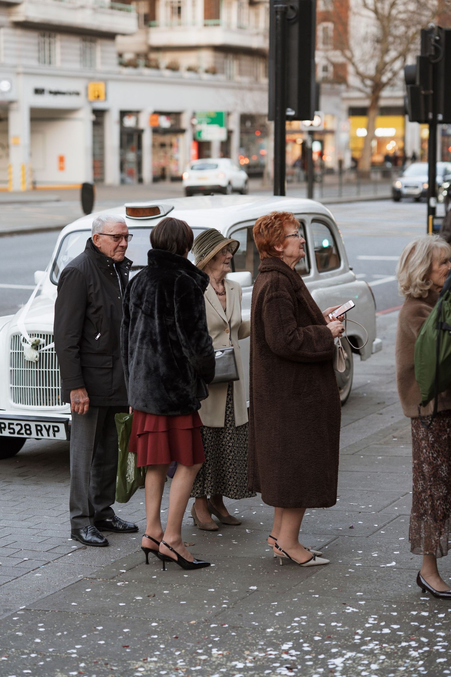 A line of people in winter coats standing on a city street in vintage black and white.