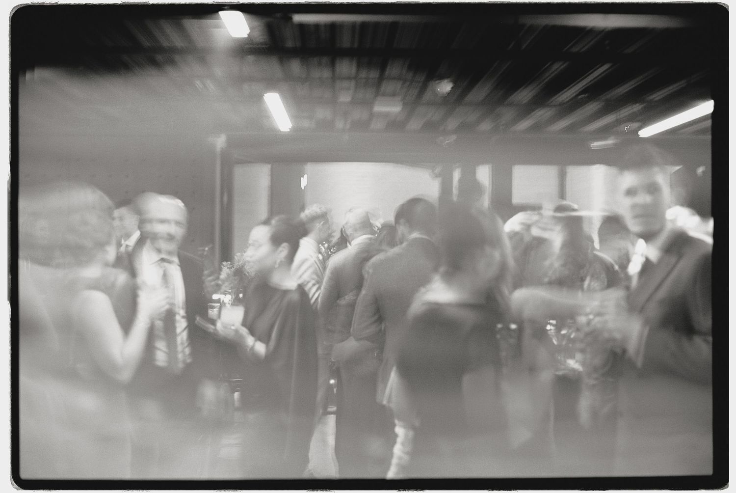 Blurred black and white photo of a crowded event space with motion.
