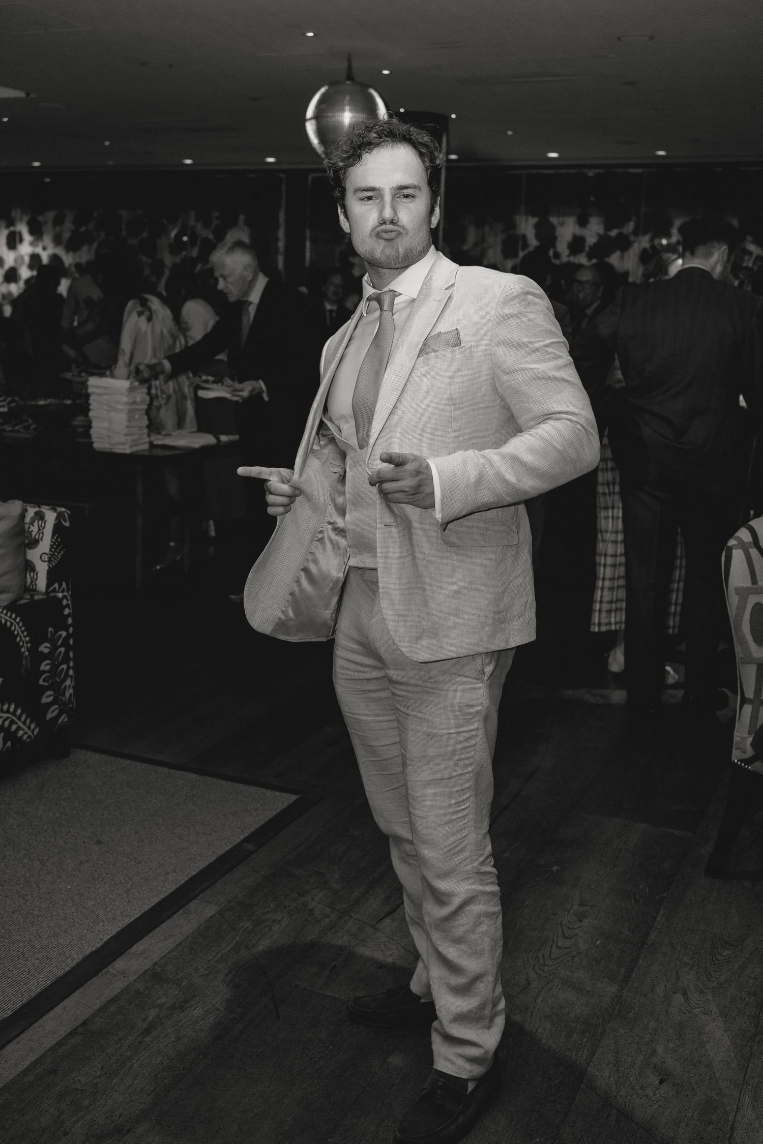 A person in a light colored suit throws a bowling ball down the lane.