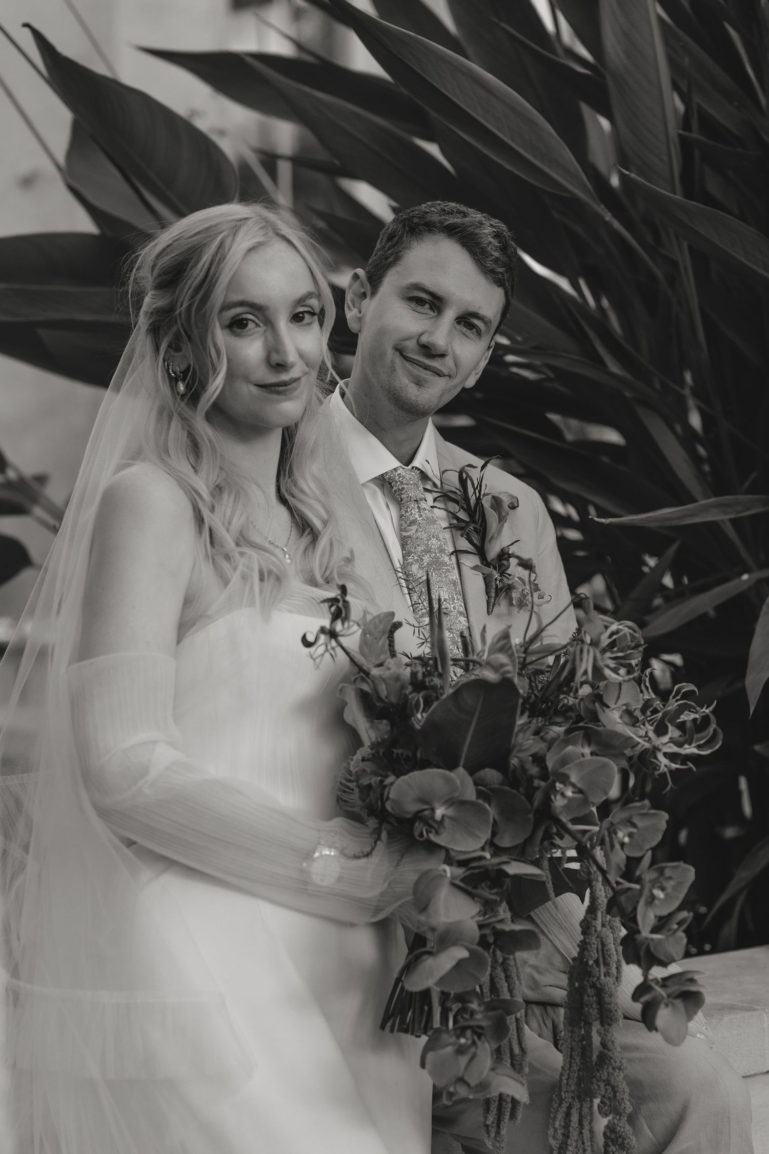 Black and white wedding portraits showing tender moments between newlyweds with floral bouquet details.