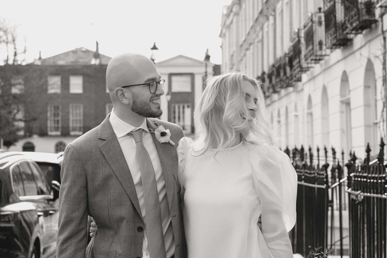 Elegant couple sharing intimate moments along historic London street with white buildings.