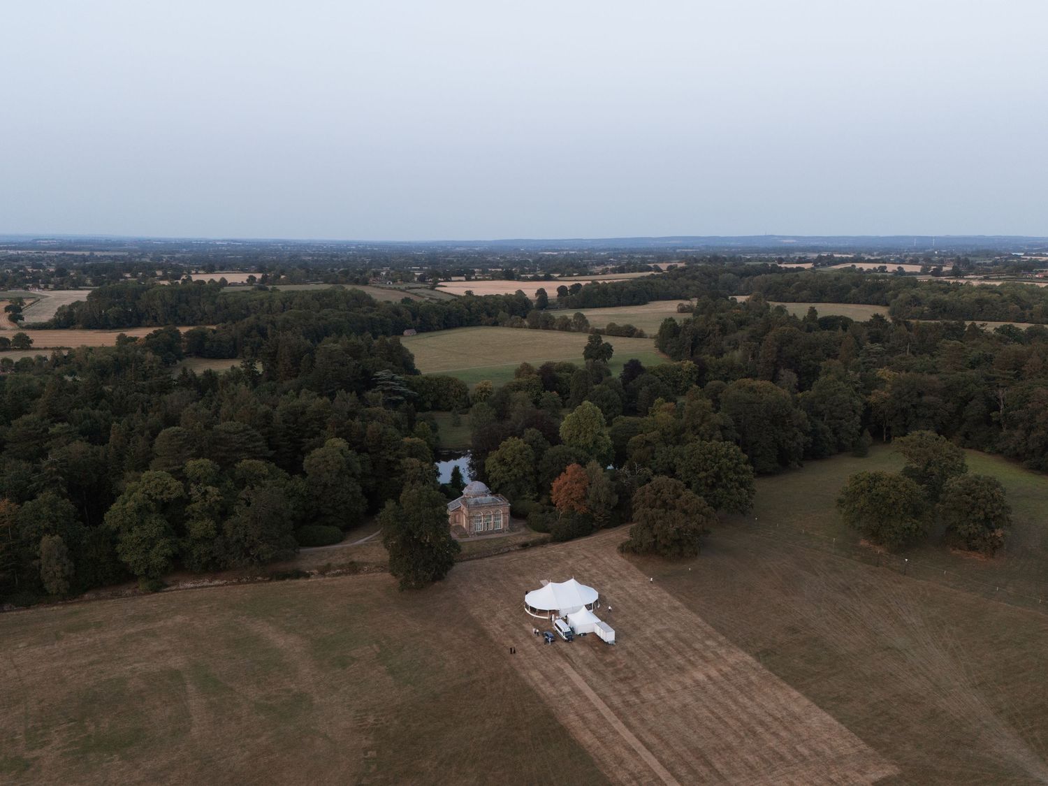 Aerial view of rural farmland and forest with scattered buildings.