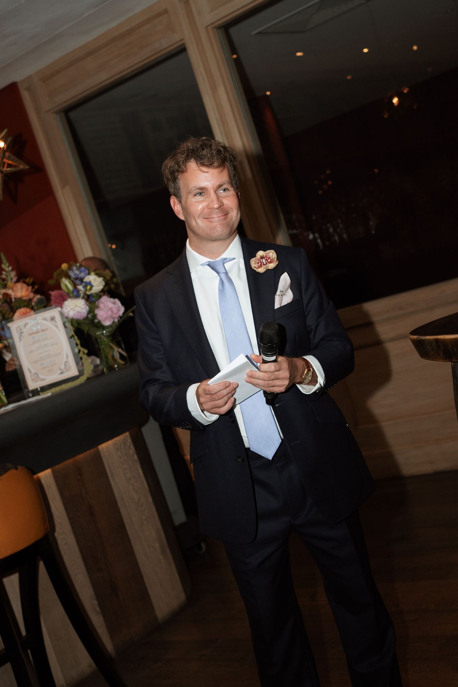 Person in formal attire holding up a phone in a dimly lit venue.