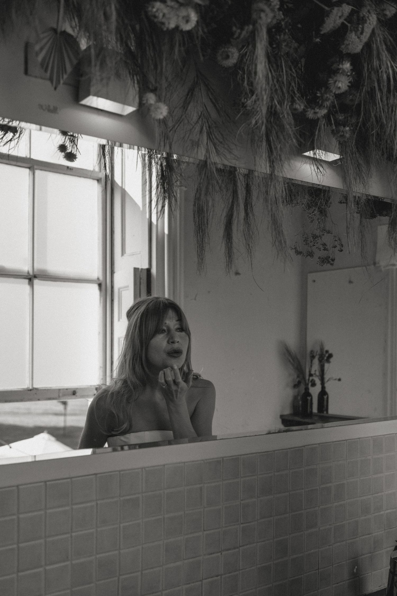 Artistic black and white bathroom scene with decorative floral arrangements hanging from the ceiling.