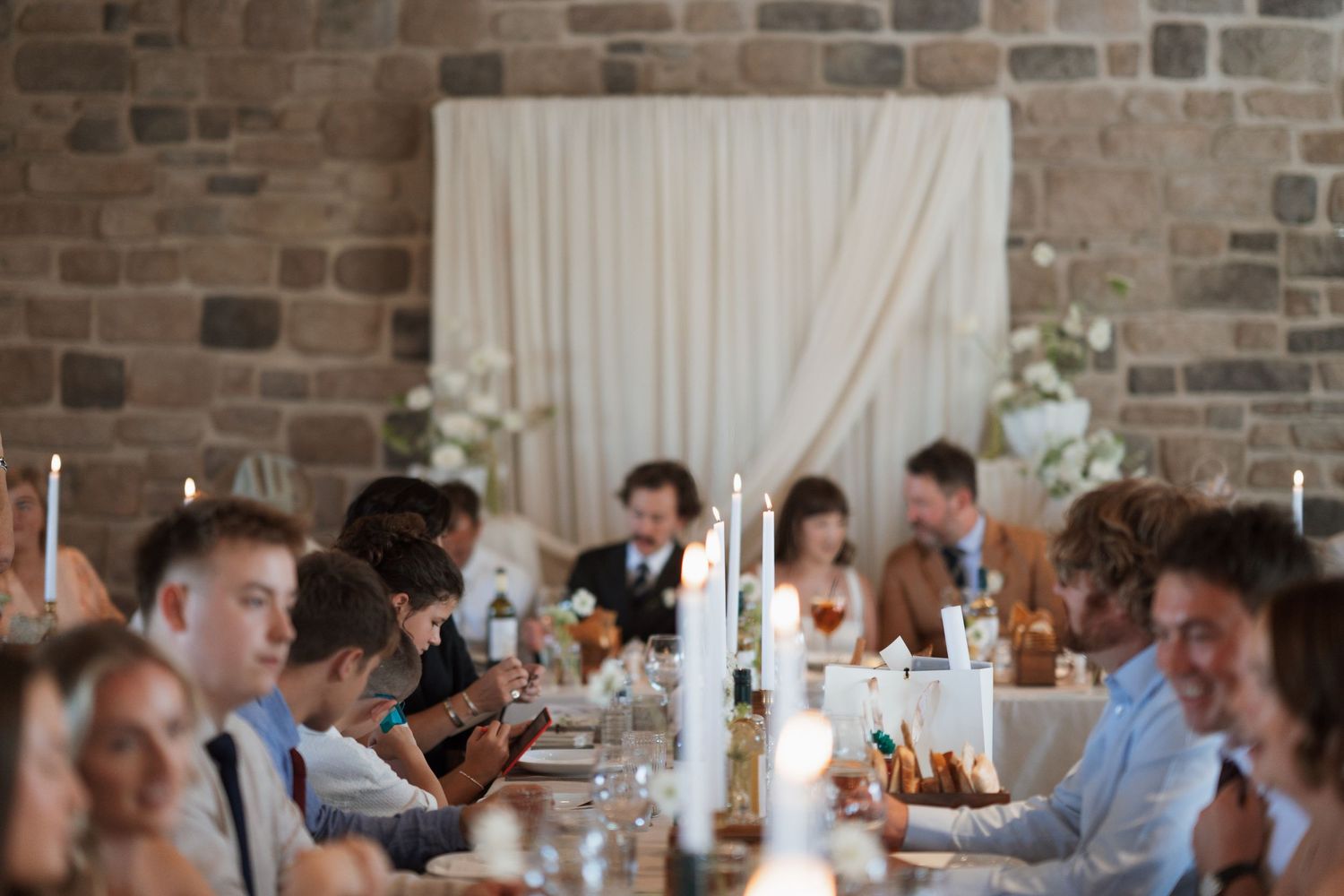 Wedding reception table settings in rustic brick venue with candlelight.