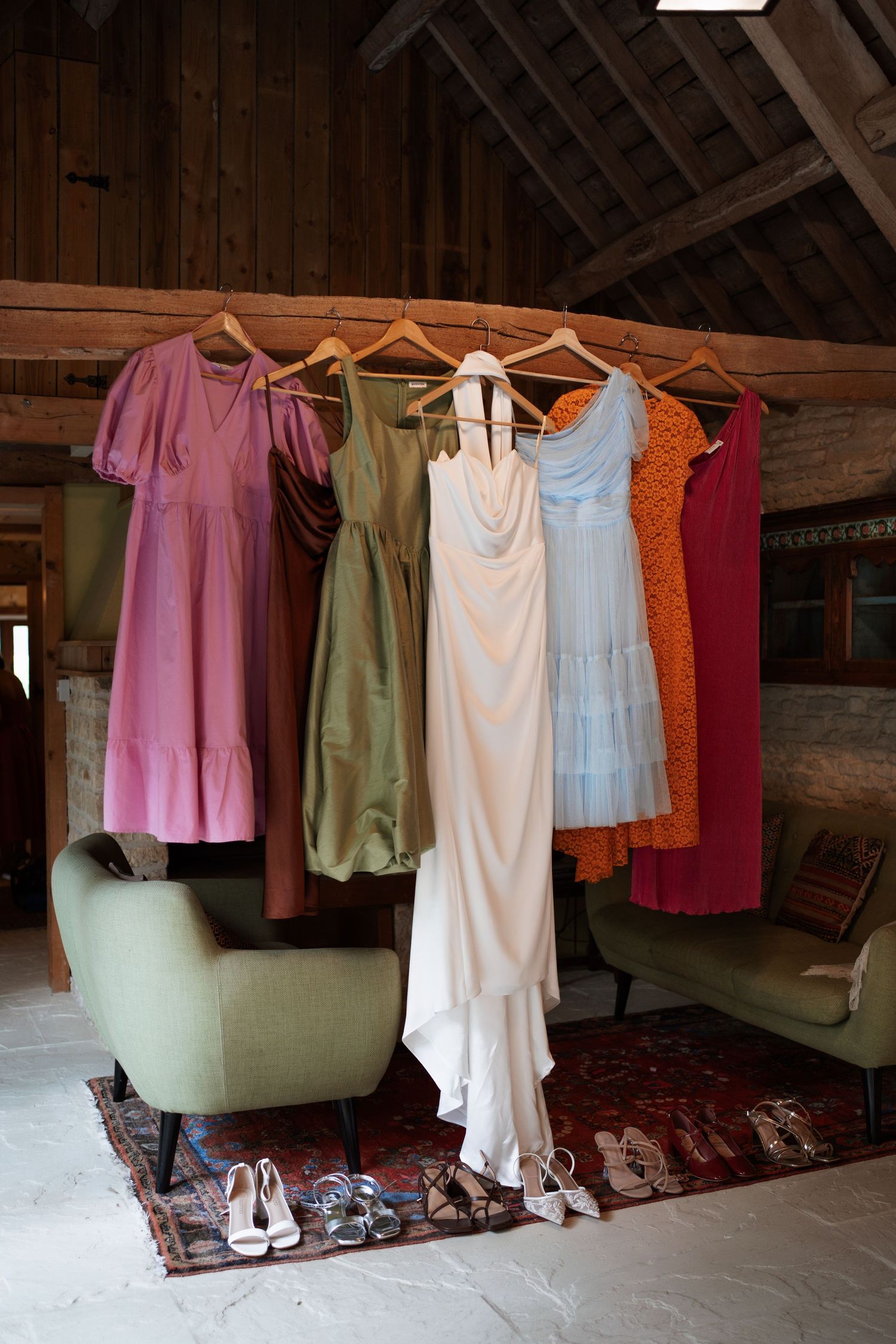 Colorful dresses and formal wear hanging on a clothesline in a rustic attic space.