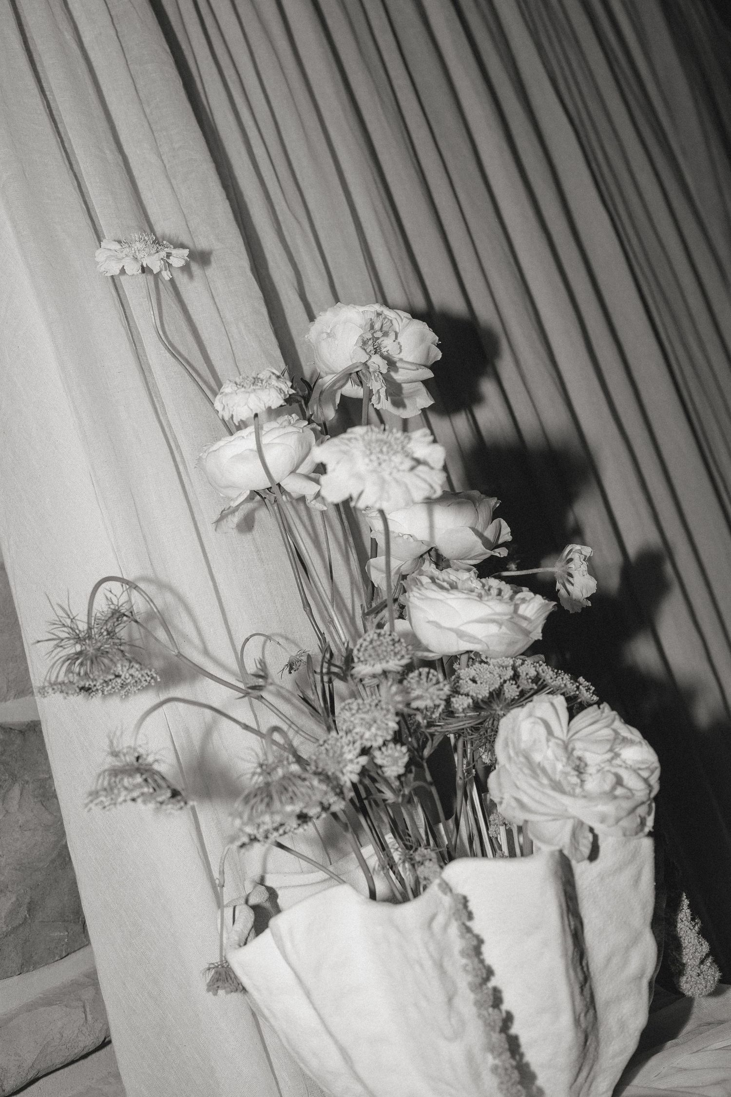 Black and white photo of roses and flowers arranged in a decorative white container.