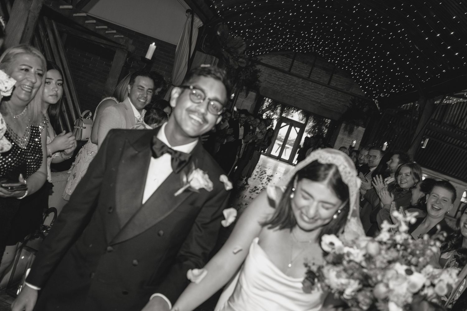 Wedding party dancing and celebrating under a starlit ceiling at an evening reception.