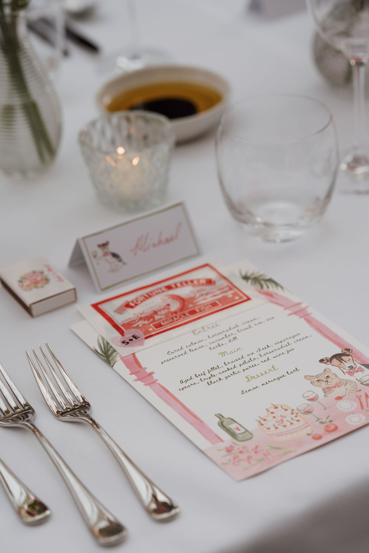 Wedding reception place settings with vintage-style menu cards and silverware.