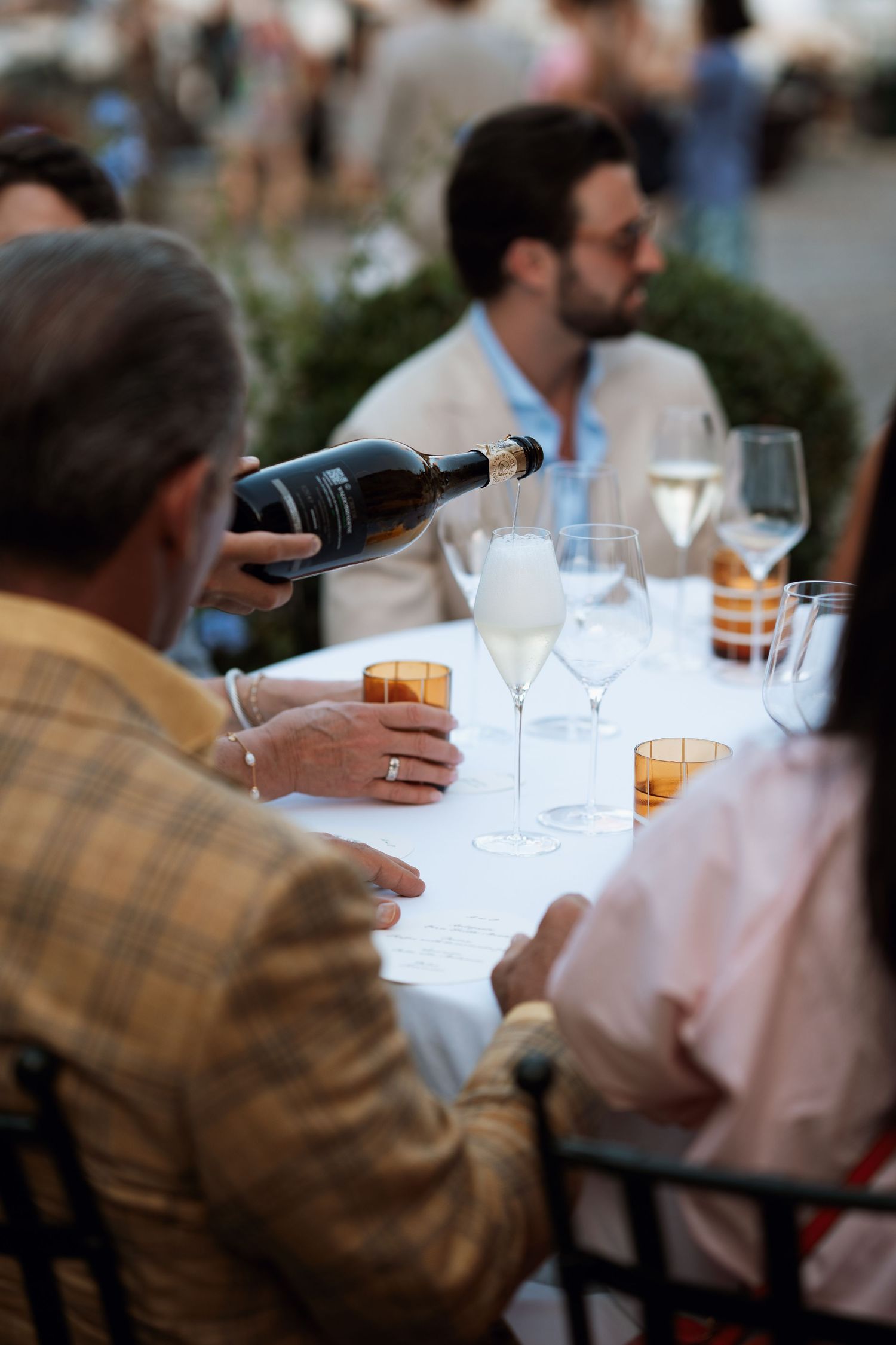 Close-up of wine glasses and table settings during an outdoor dining event.