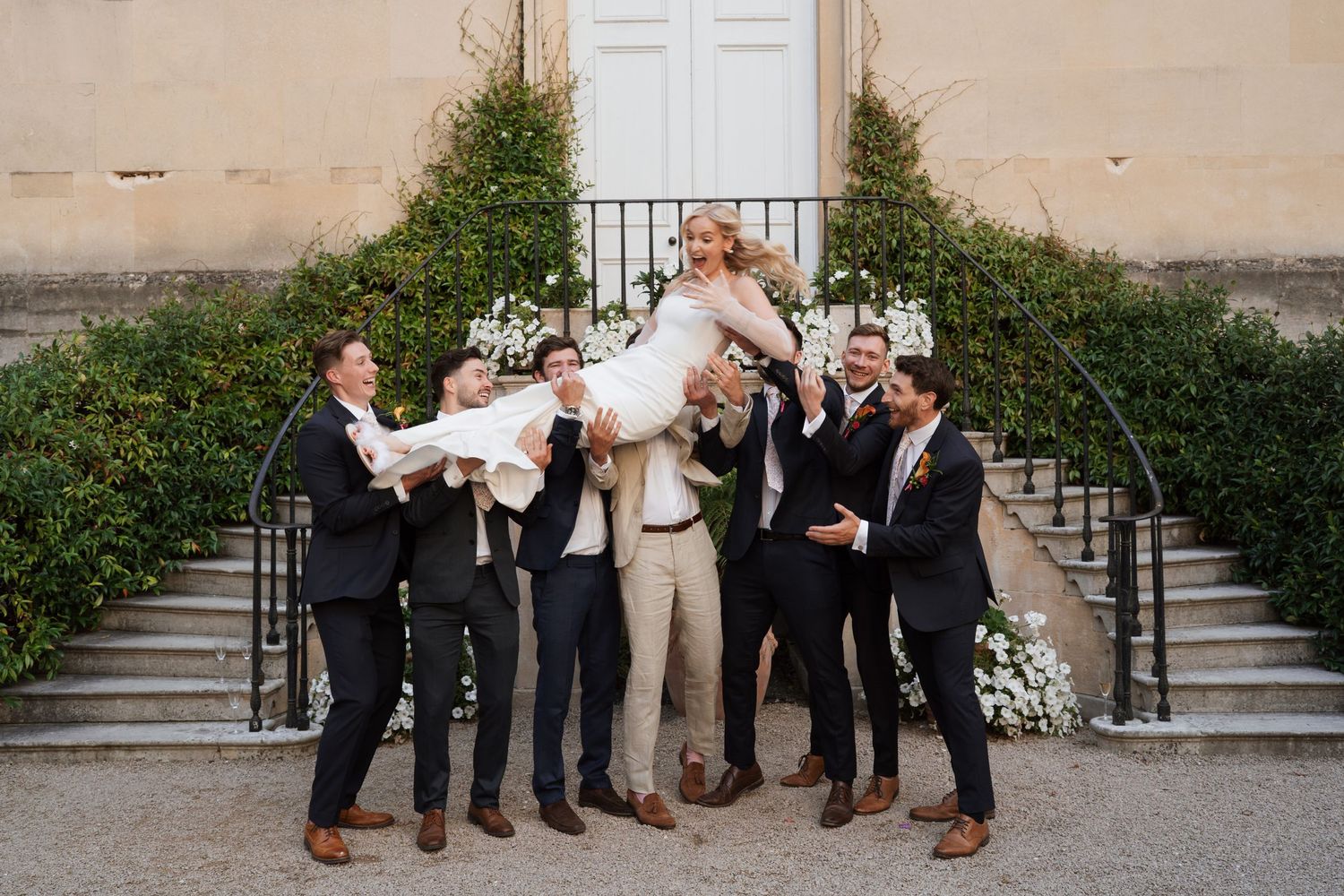 Wedding party members lined up on stone steps for formal photos.