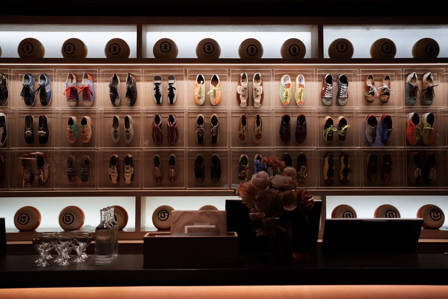 Long display shelf with rows of shoes arranged neatly against a wall.