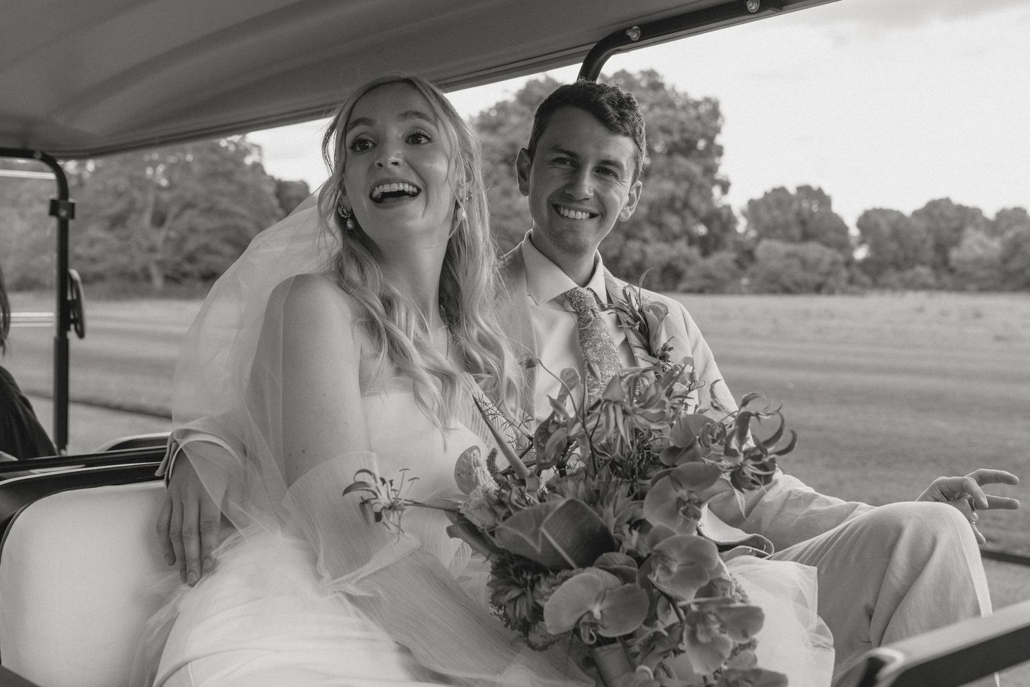 Wedding party travels in a vintage car through countryside with bouquets.