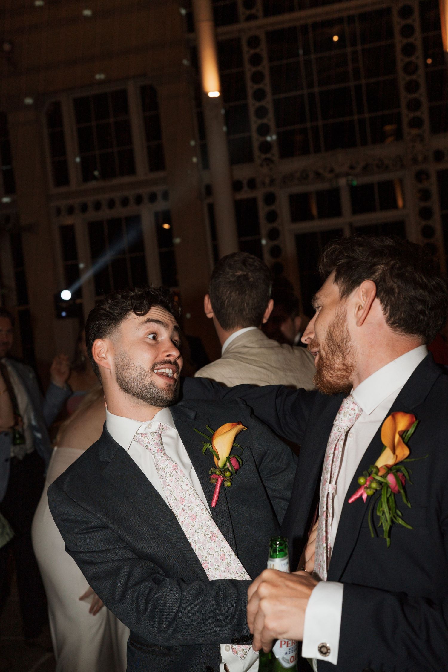 Wedding party members in formal attire laughing and embracing during celebration.