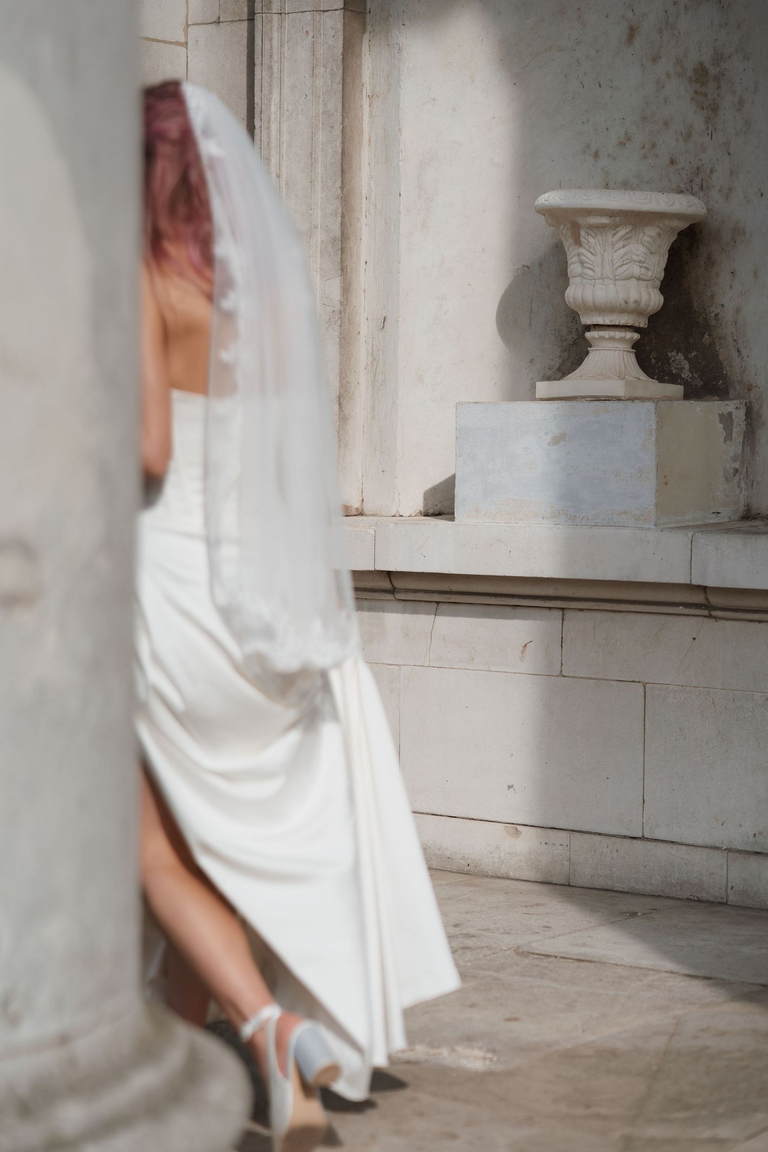 Flowing white wedding dress movement captured in architectural setting with stone columns.